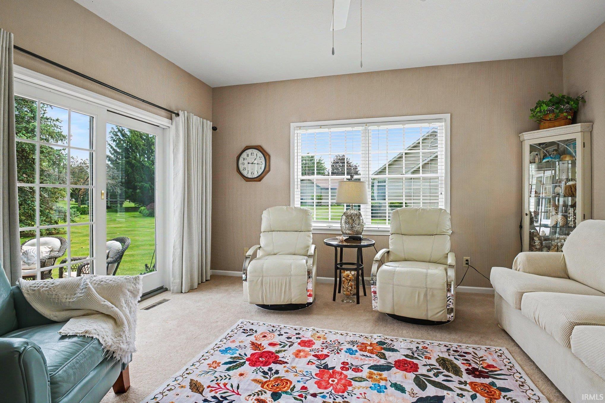 Neutral-toned wall finishes, light-colored carpet, and a white ceiling fan