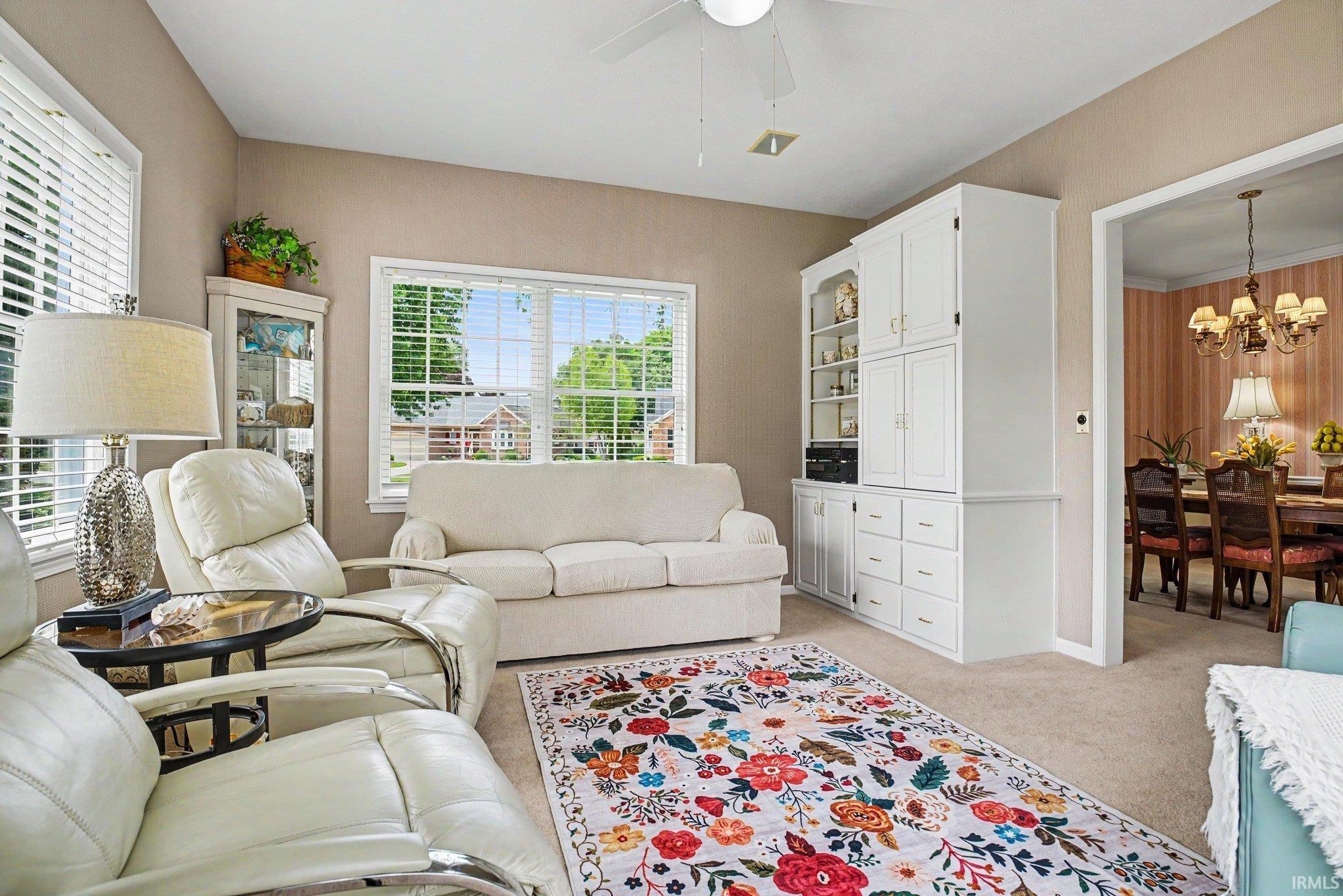 Spacious living area featuring neutral carpet flooring and ample natural light from multiple windows