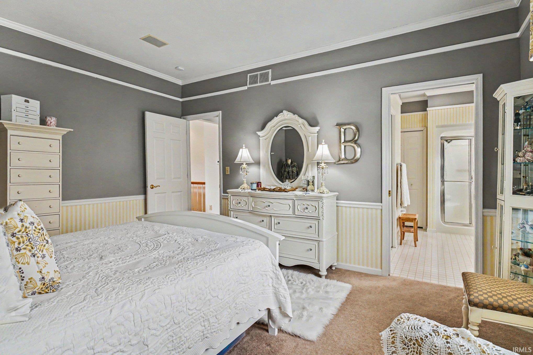 Carpeted room with crown molding, wainscoting, and a neutral wall color