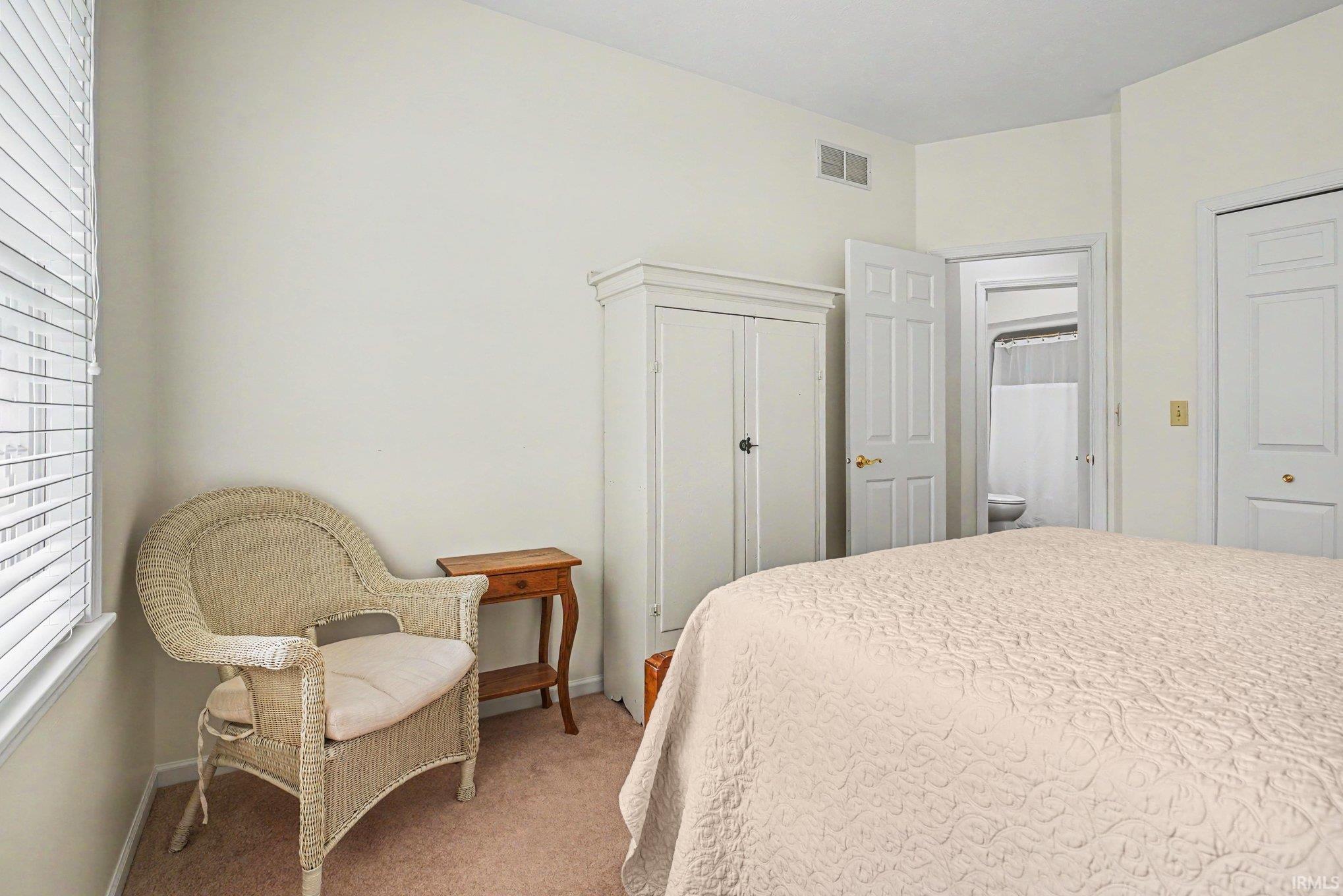 Neutral-toned bedroom featuring wall-to-wall carpeting and white window blinds