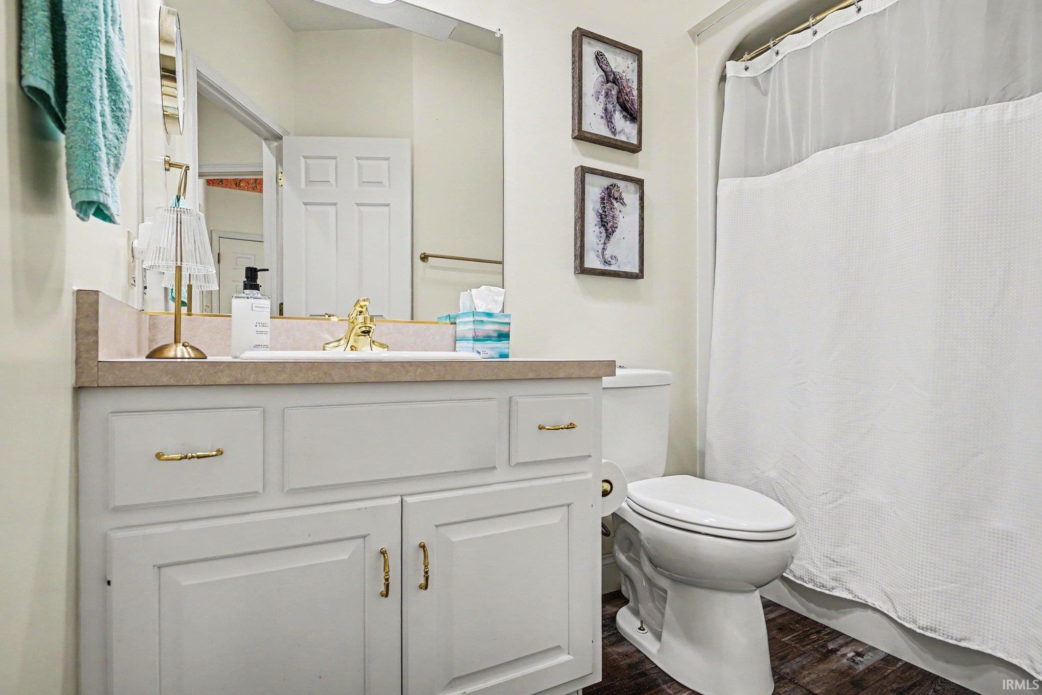 Bathroom vanity featuring white cabinetry, gold-tone hardware, and a light-toned countertop with an integrated sink and gold-tone faucet