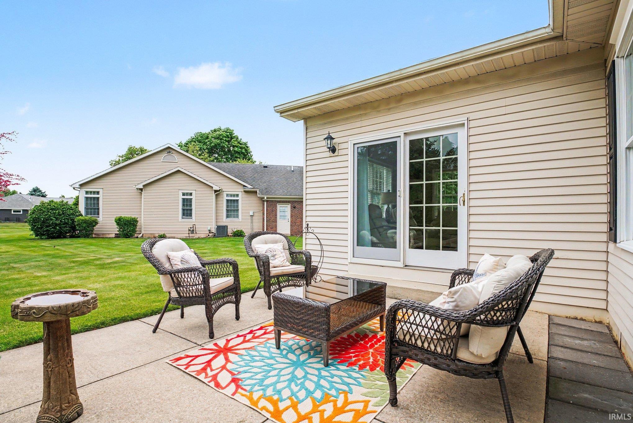 Concrete patio featuring a sliding glass door entry to the interior, exterior wall sconce, and a manicured lawn