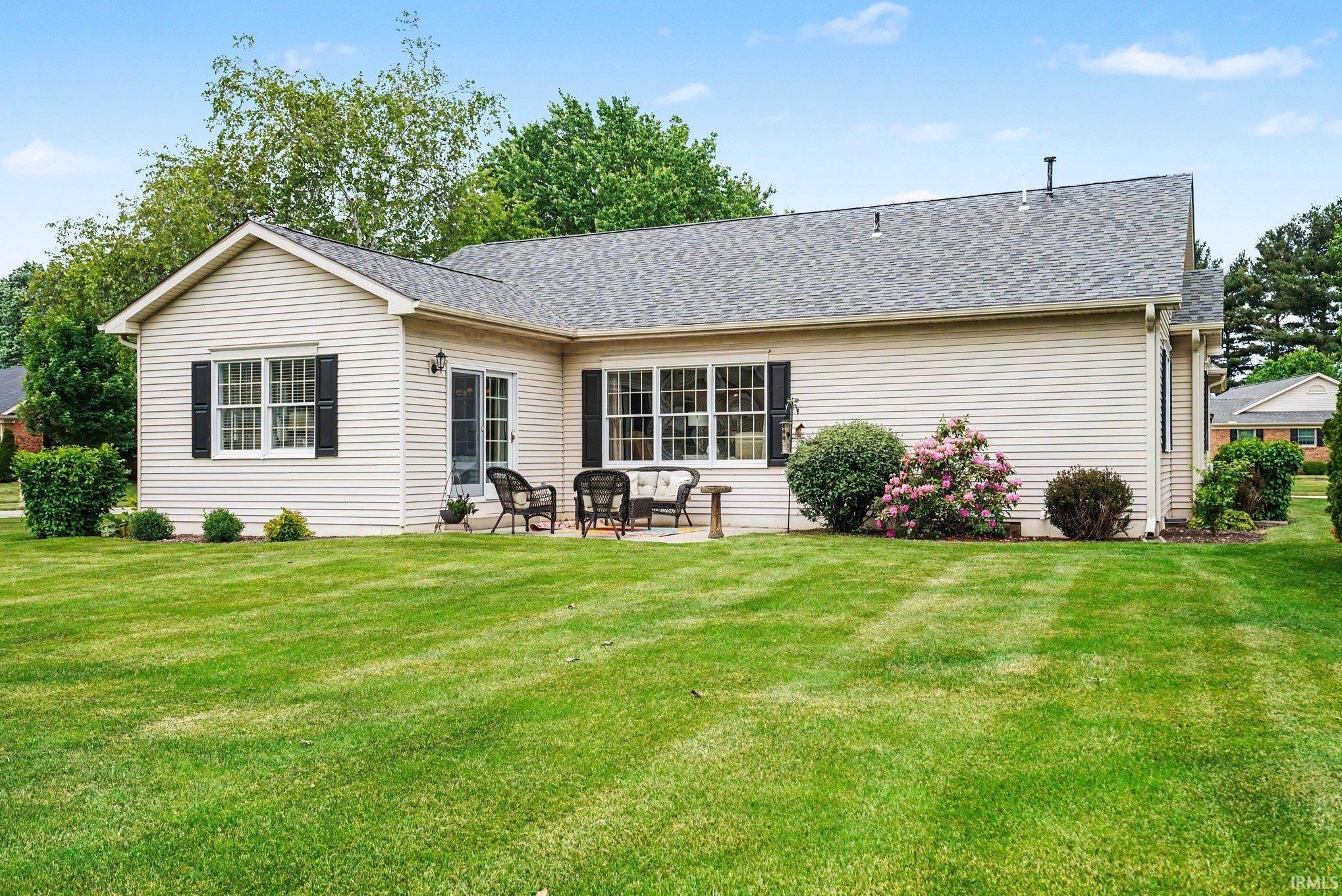 Cream-colored siding exterior featuring black louvered shutters and a charcoal shingle roof