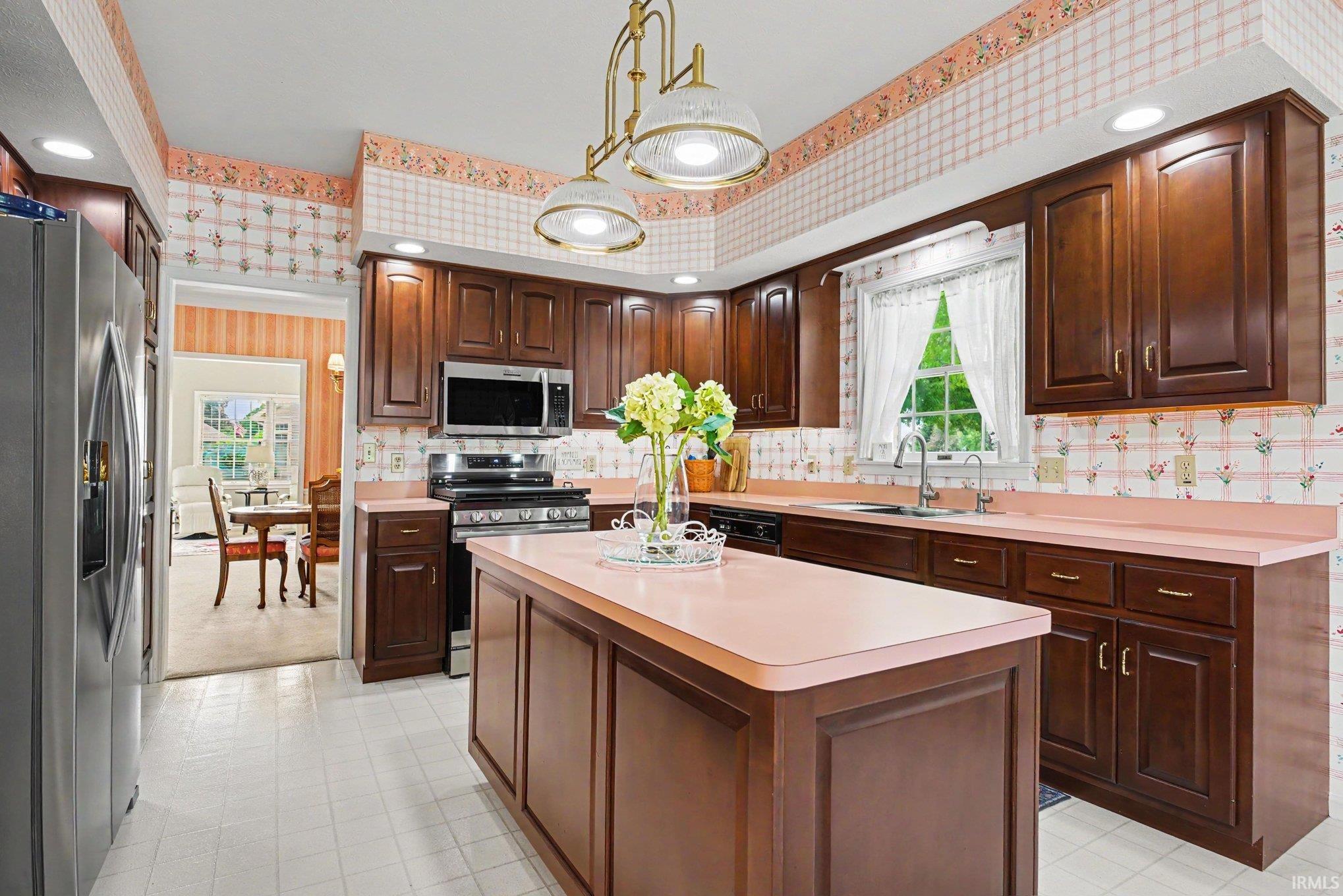 Kitchen featuring wood-finish cabinetry, a central island, and light-toned countertops