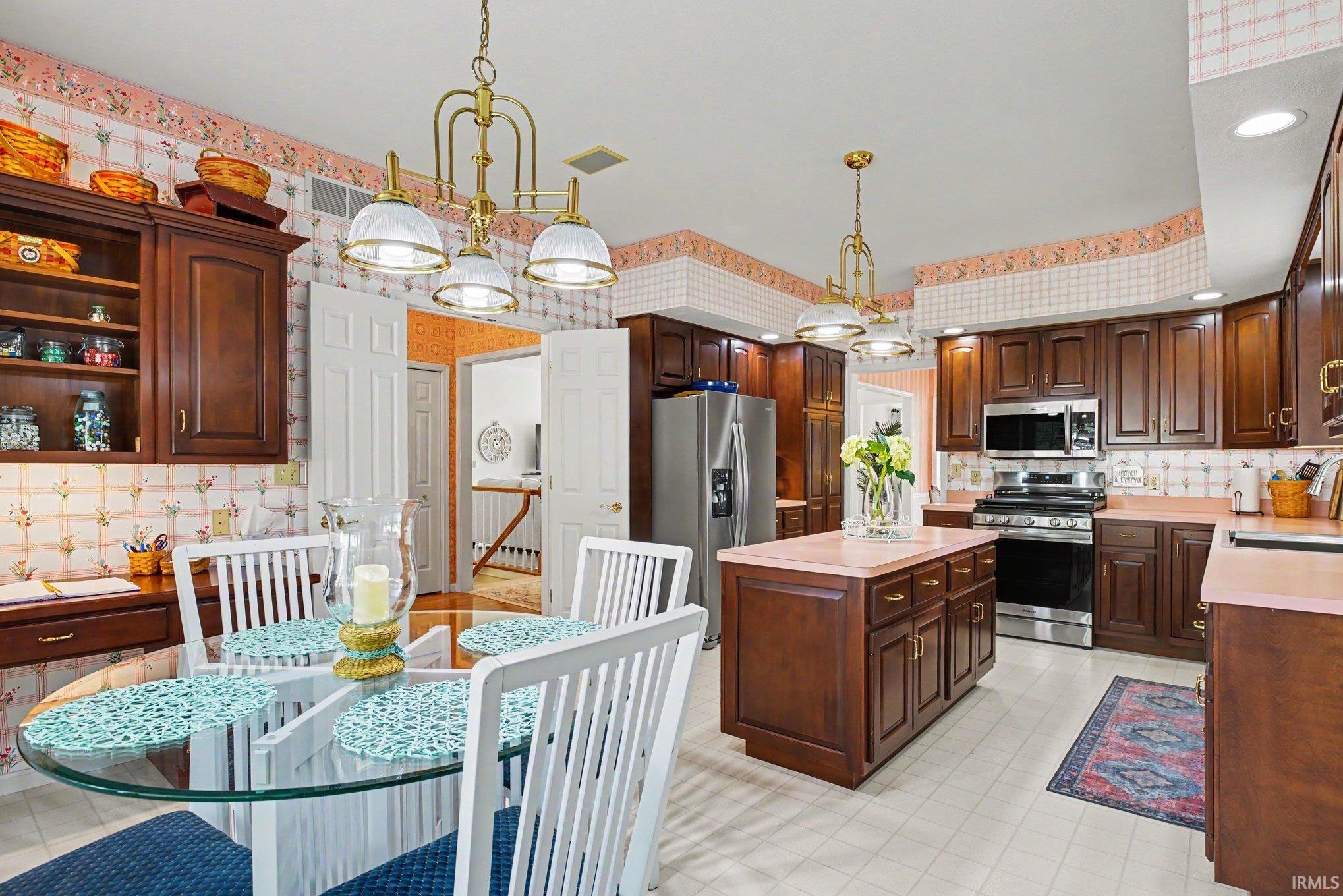 Kitchen featuring extensive wood cabinetry, a central island with countertop, and stainless steel appliances