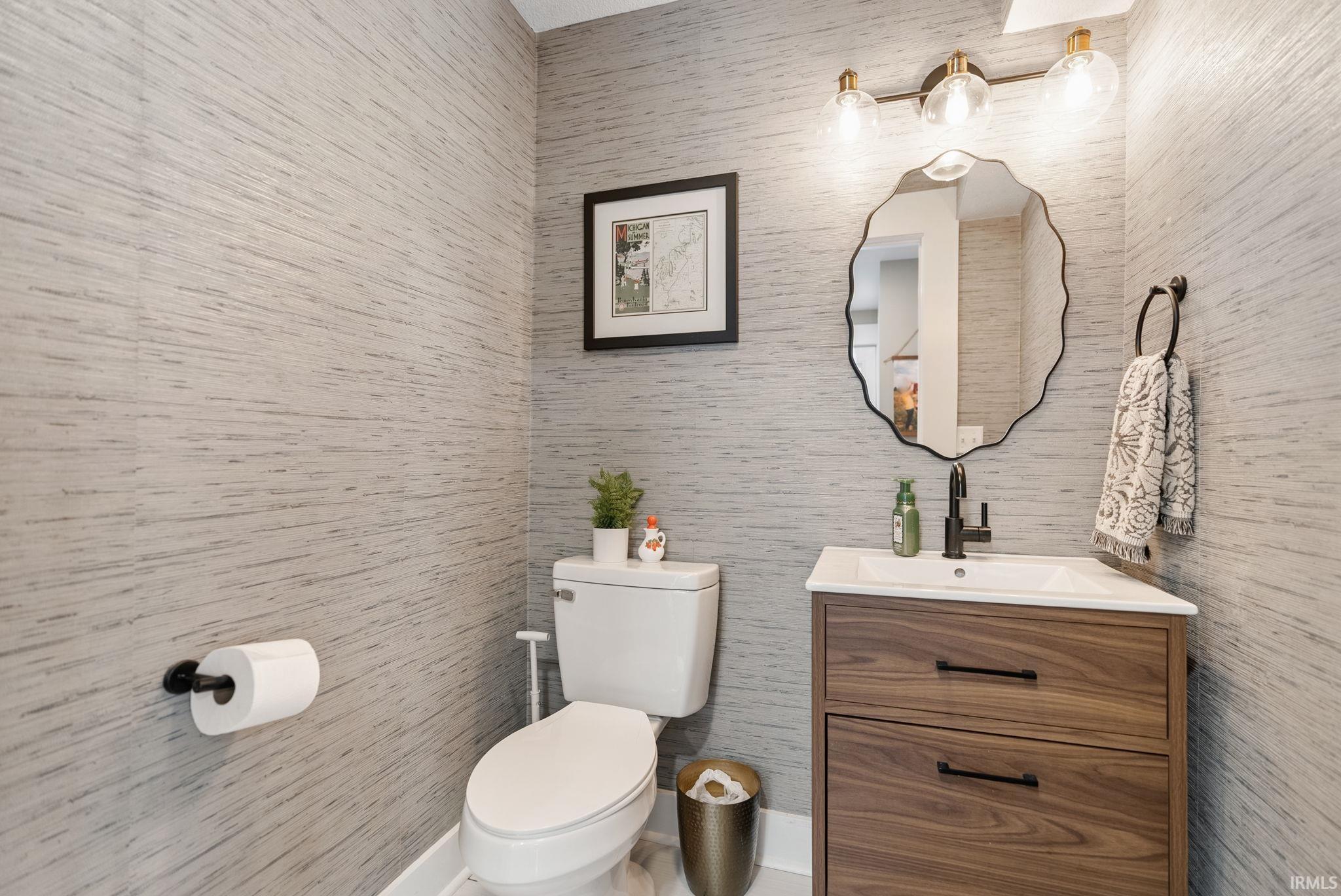 Powder room featuring textured wall covering, a contemporary vanity with wood-finish cabinetry, a white rectangular sink, and a matte black faucet