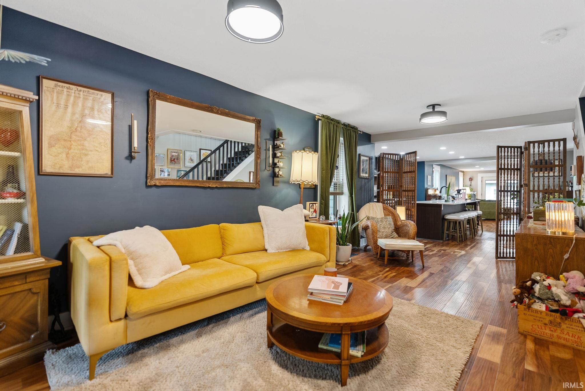 Living area featuring wood-finish flooring, a contemporary ceiling fixture, a built-in wall sconce, and a wood-framed mirror