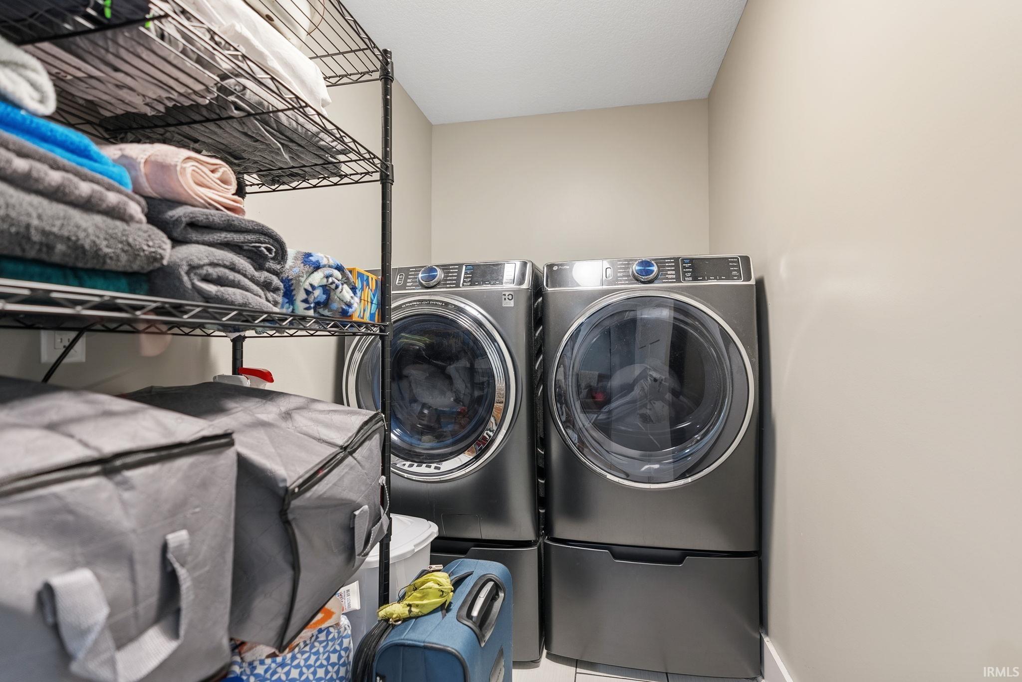 Dedicated laundry area featuring a full-size washer and dryer set with pedestal drawers
