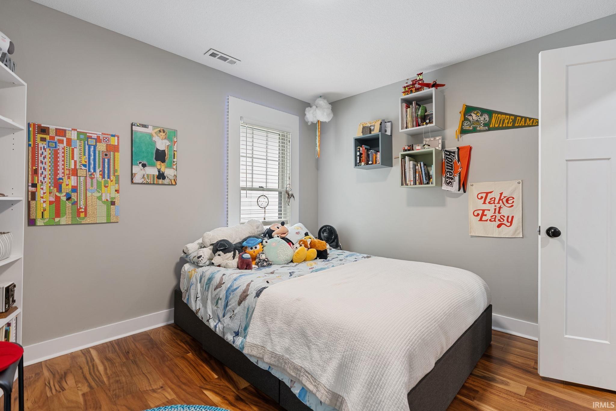 Bedroom featuring wood-finish flooring, white baseboards, and light gray walls