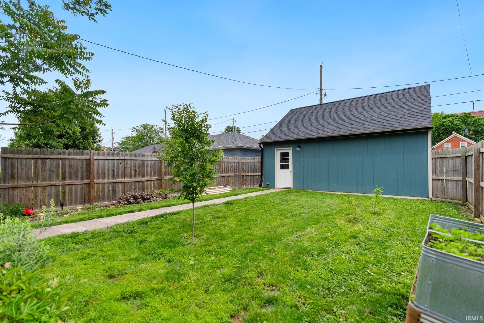 Detached structure featuring teal siding, a single white door, and an asphalt shingle roof