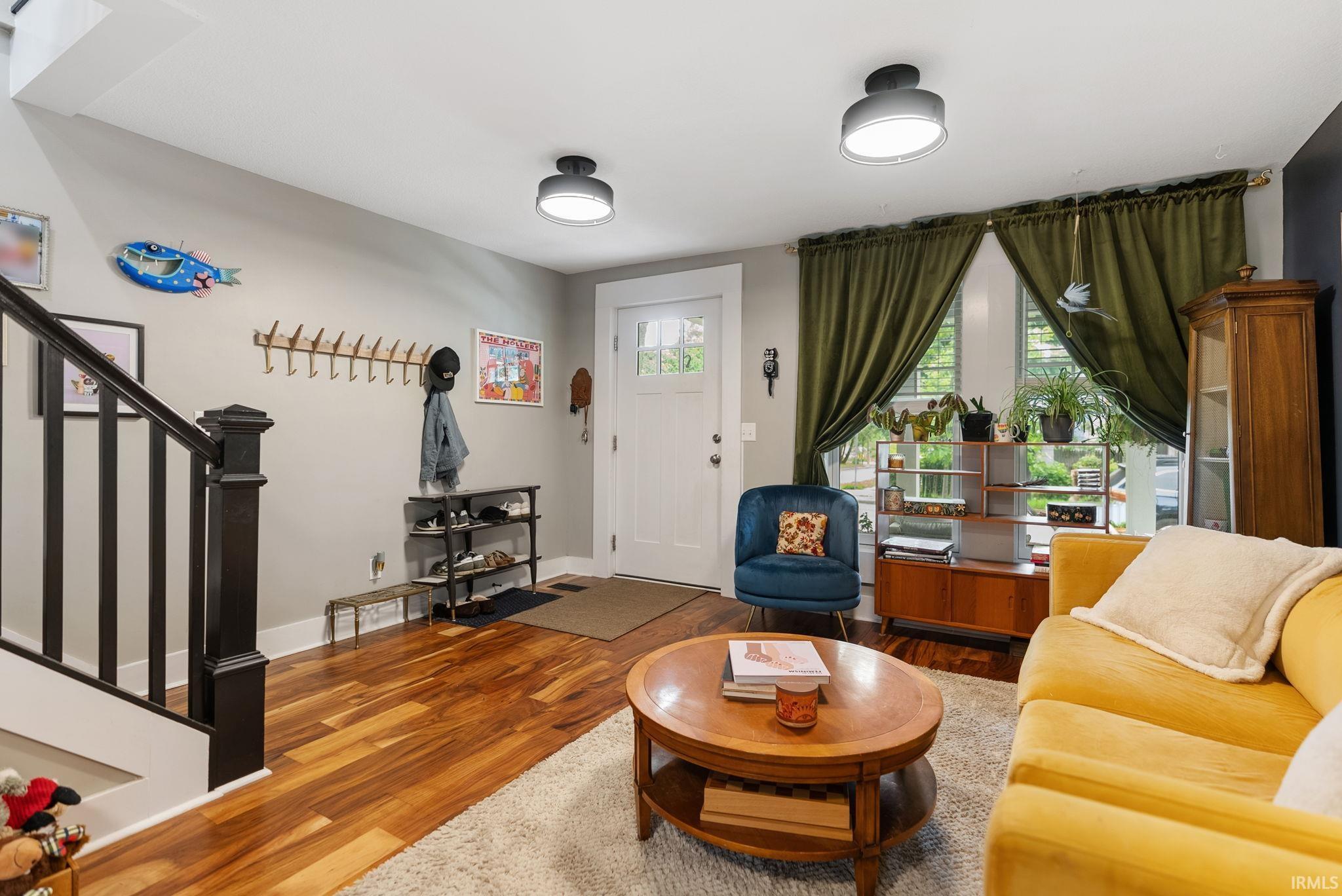 Bright living area featuring wood-finish flooring, white trim, and a white paneled entry door with glass inserts