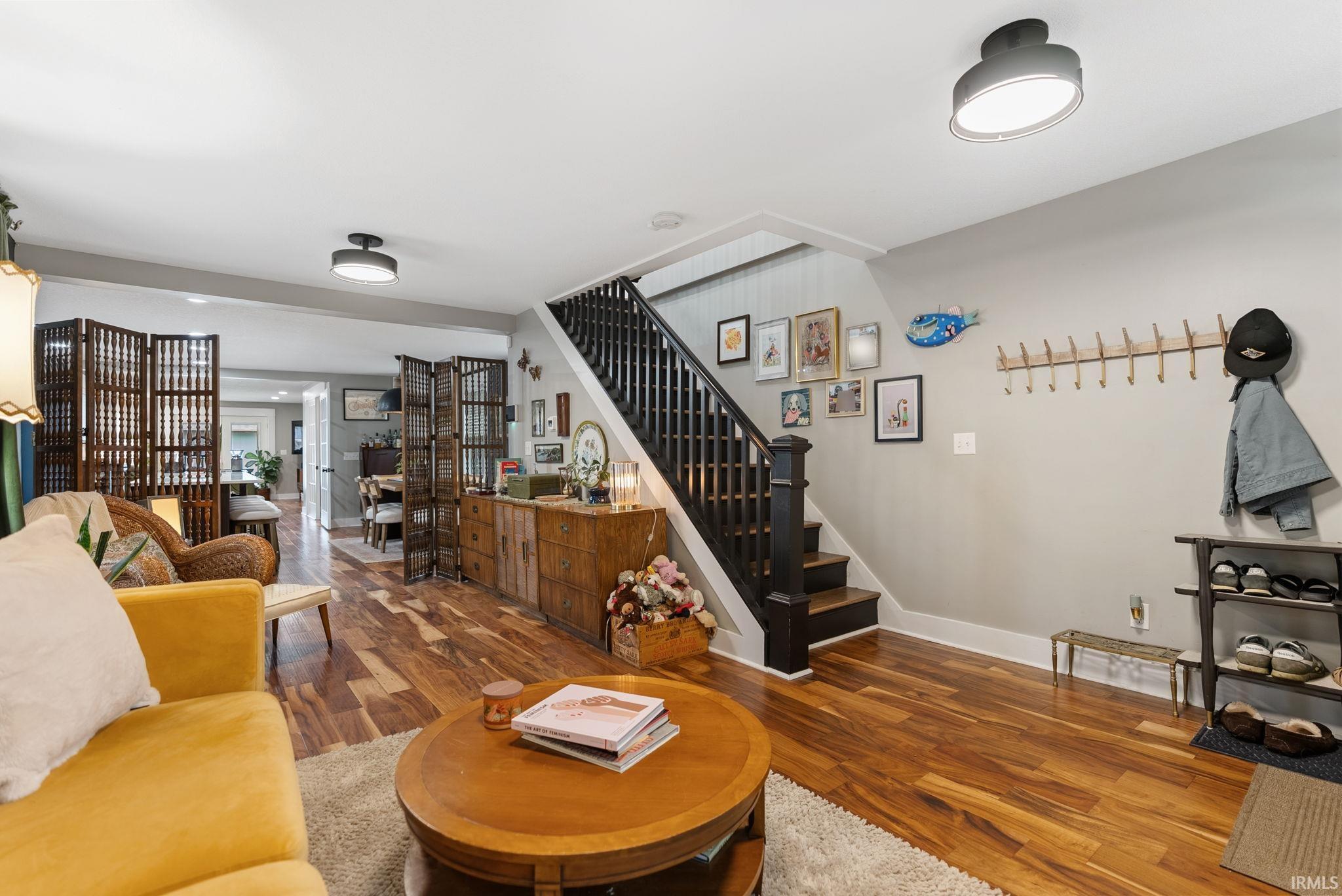 Wood-finish flooring extends throughout this open-concept living area, complemented by a dark wood staircase with white risers