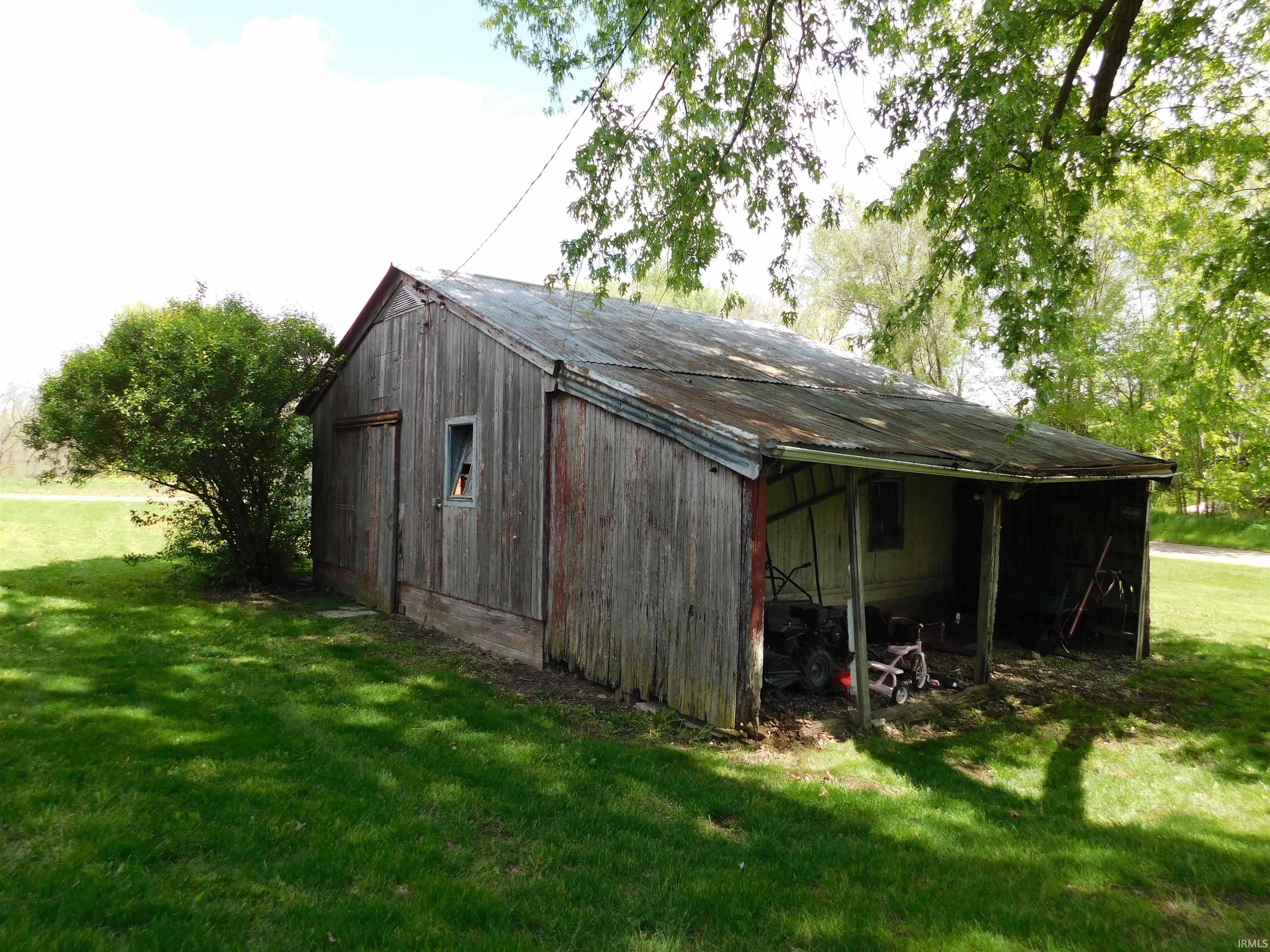 Wood-sided outbuilding featuring a corrugated metal roof and an integrated covered lean-to area