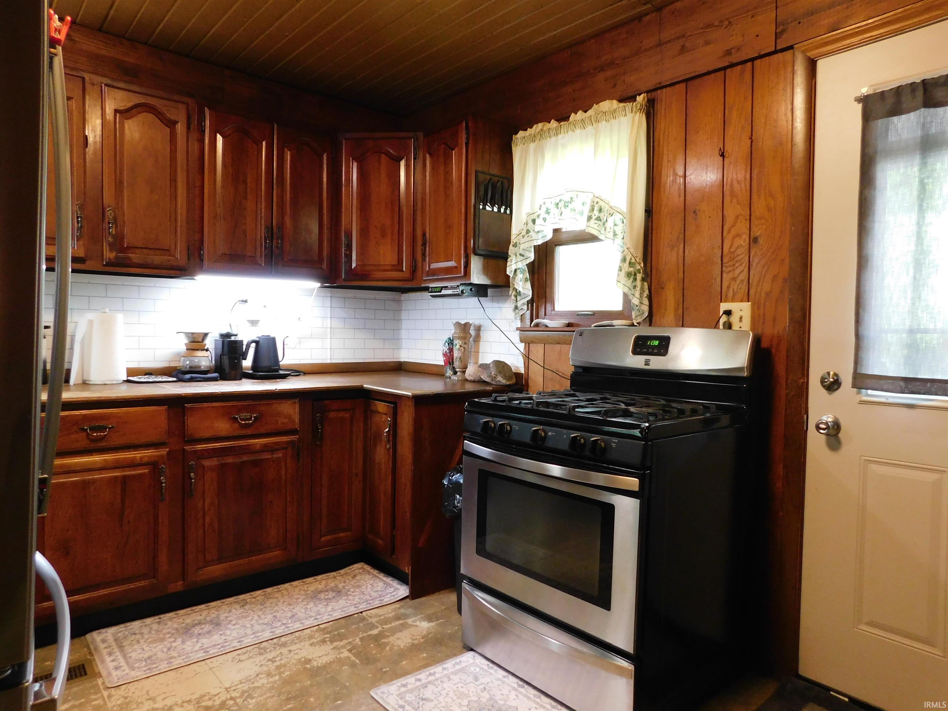 Kitchen featuring rich wood cabinetry, subway tile backsplash, and wood-finish ceiling