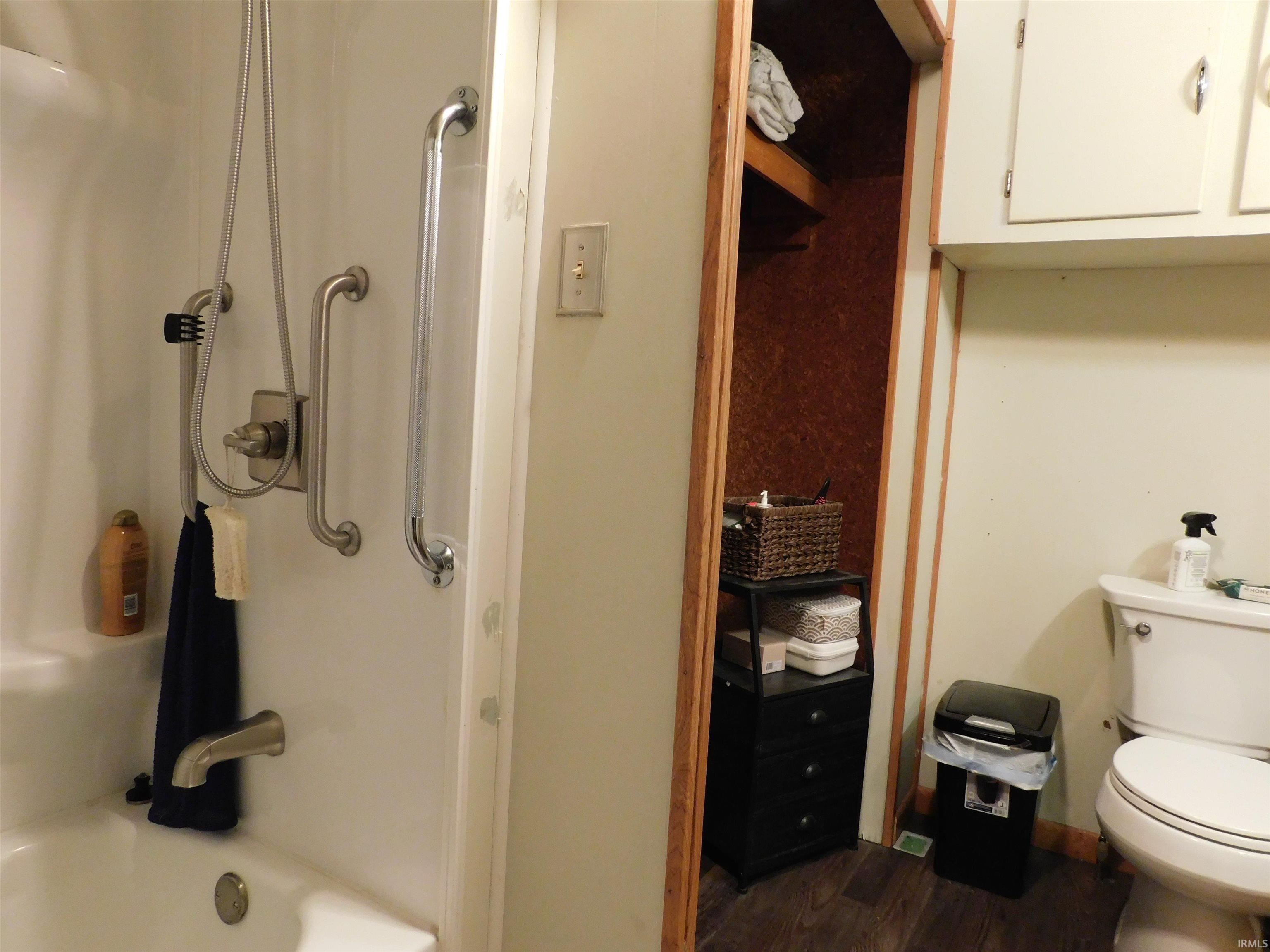 White tub-shower combination featuring grab bars and a handheld showerhead
