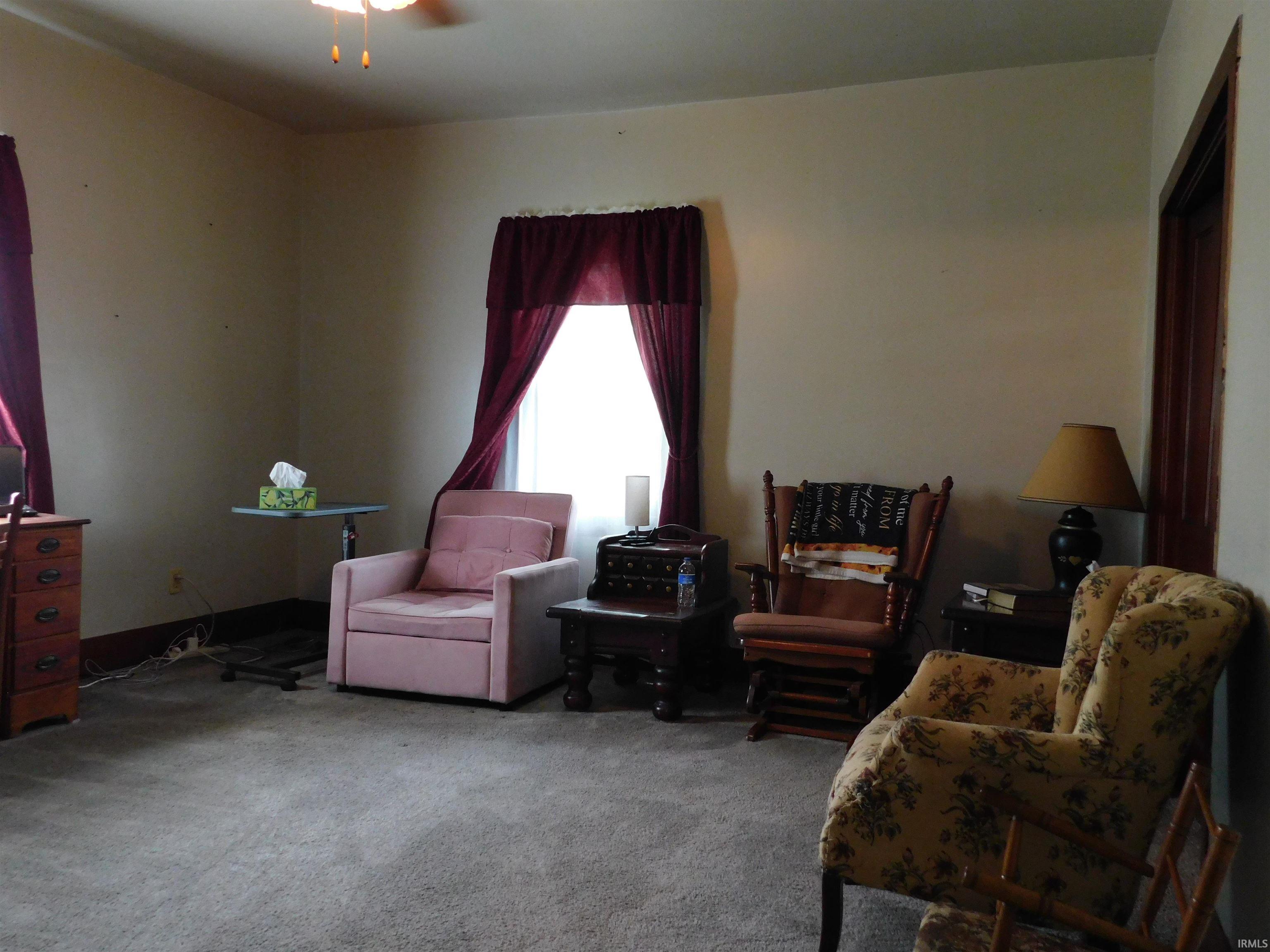 Carpeted interior room with neutral-toned walls, featuring a ceiling fan with integrated lighting and baseboard trim