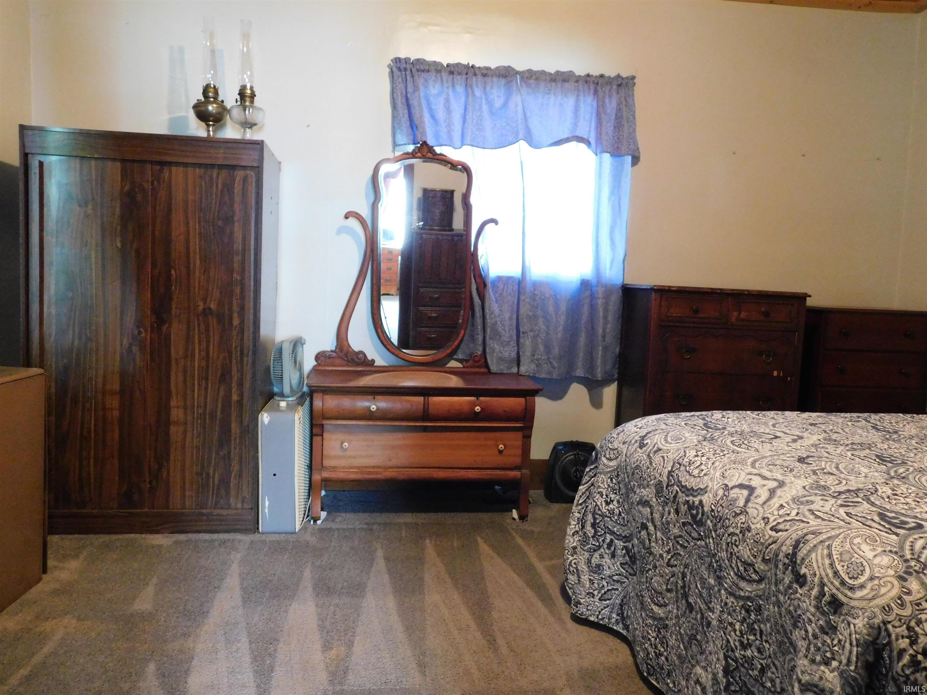 Carpeted bedroom featuring a window with natural light, a built-in closet with wood-finish doors, and light-colored walls