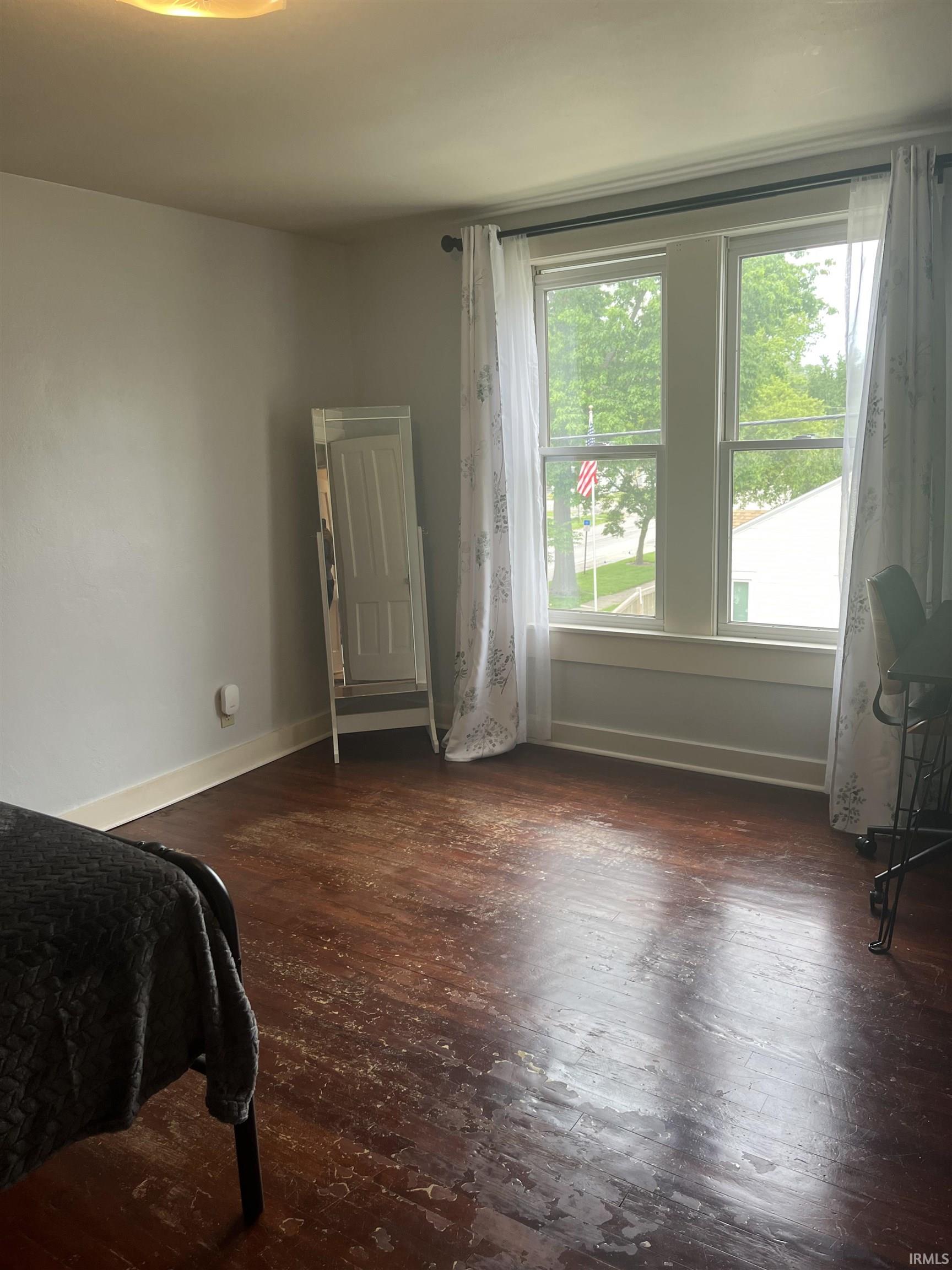 Room featuring wood-finish flooring, white baseboards, and light gray walls