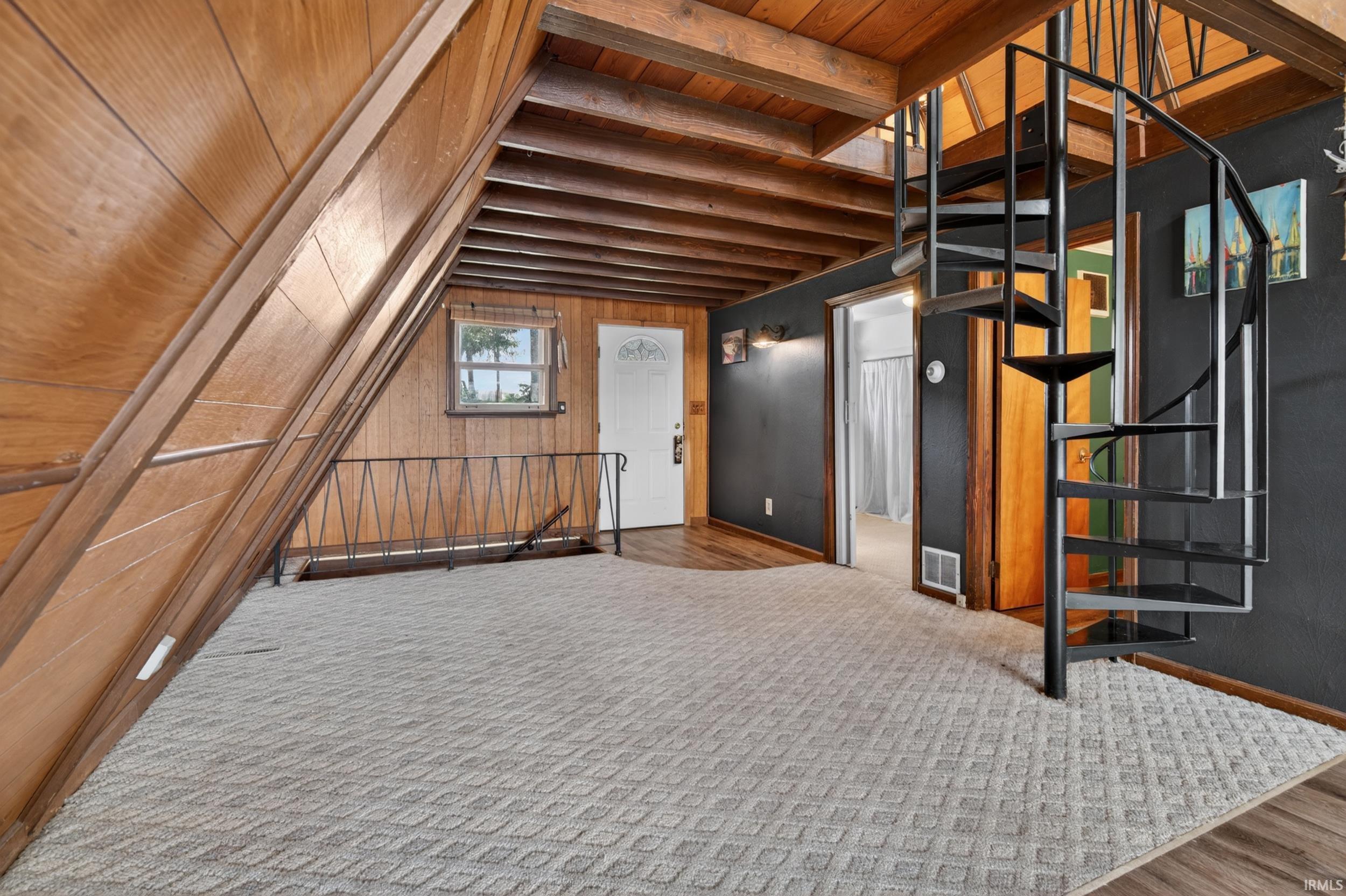 Spacious interior featuring a prominent spiral staircase, wood-finish flooring, and exposed wood beams