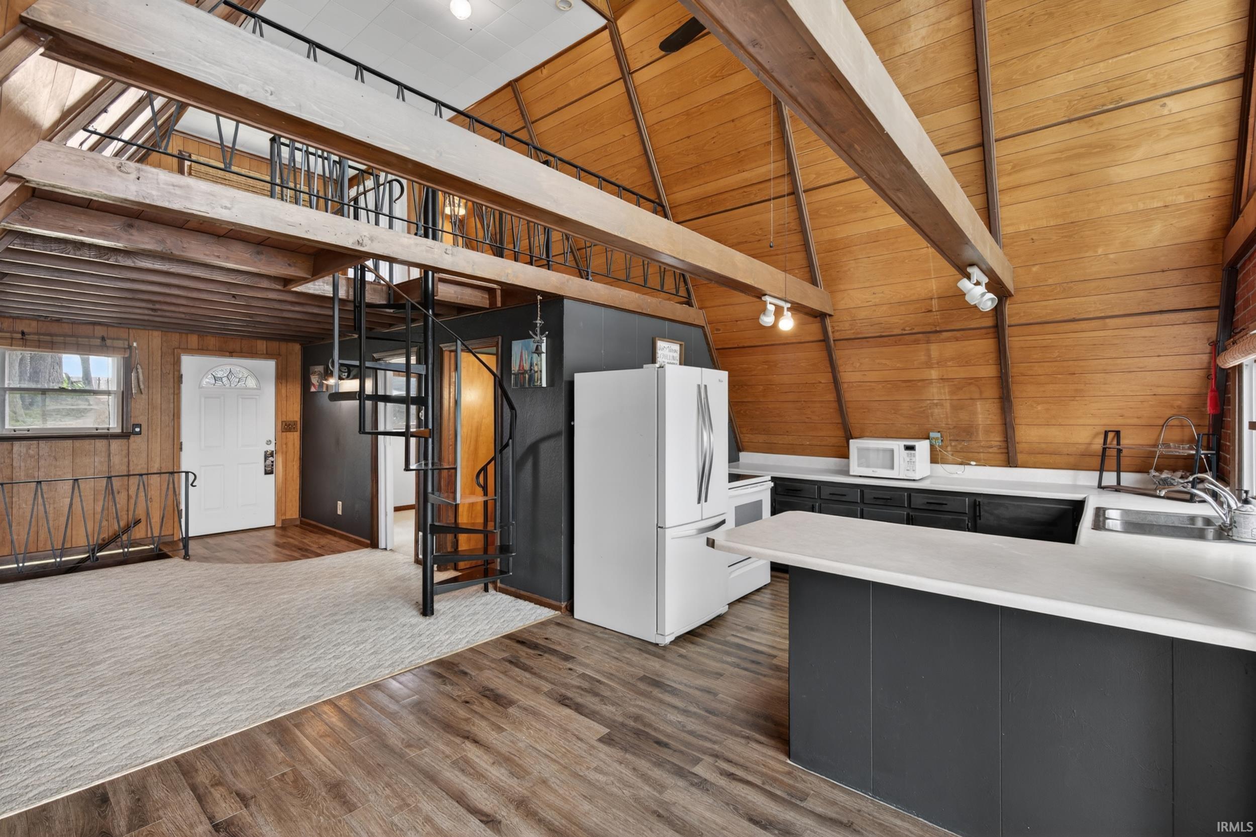 Interior featuring wood-finish flooring, a spiral staircase, and an open loft area