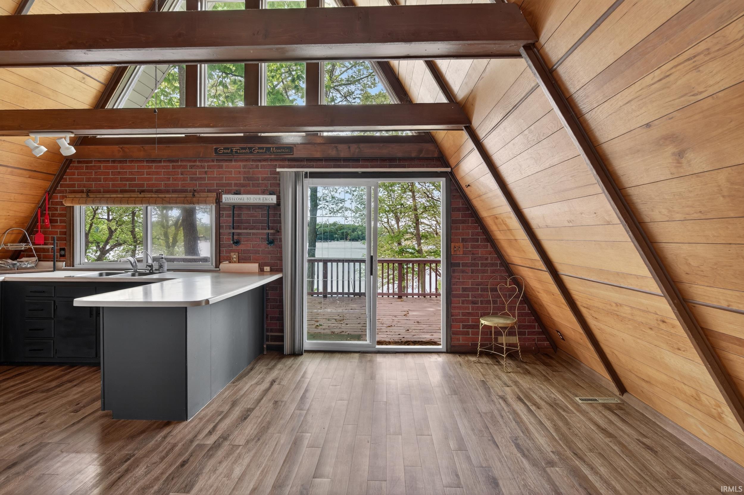 A-frame interior featuring wood-finish flooring, exposed wood beams, and sloped wood-paneled walls