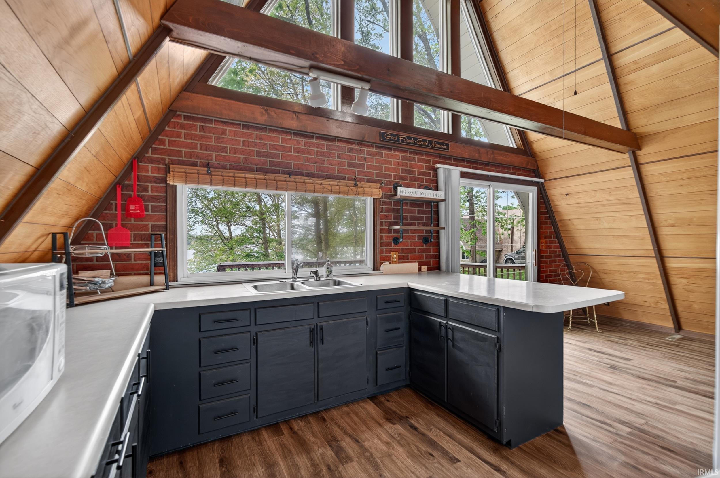 Kitchen featuring dark cabinetry, light countertops, a stainless steel double sink, and wood-finish flooring
