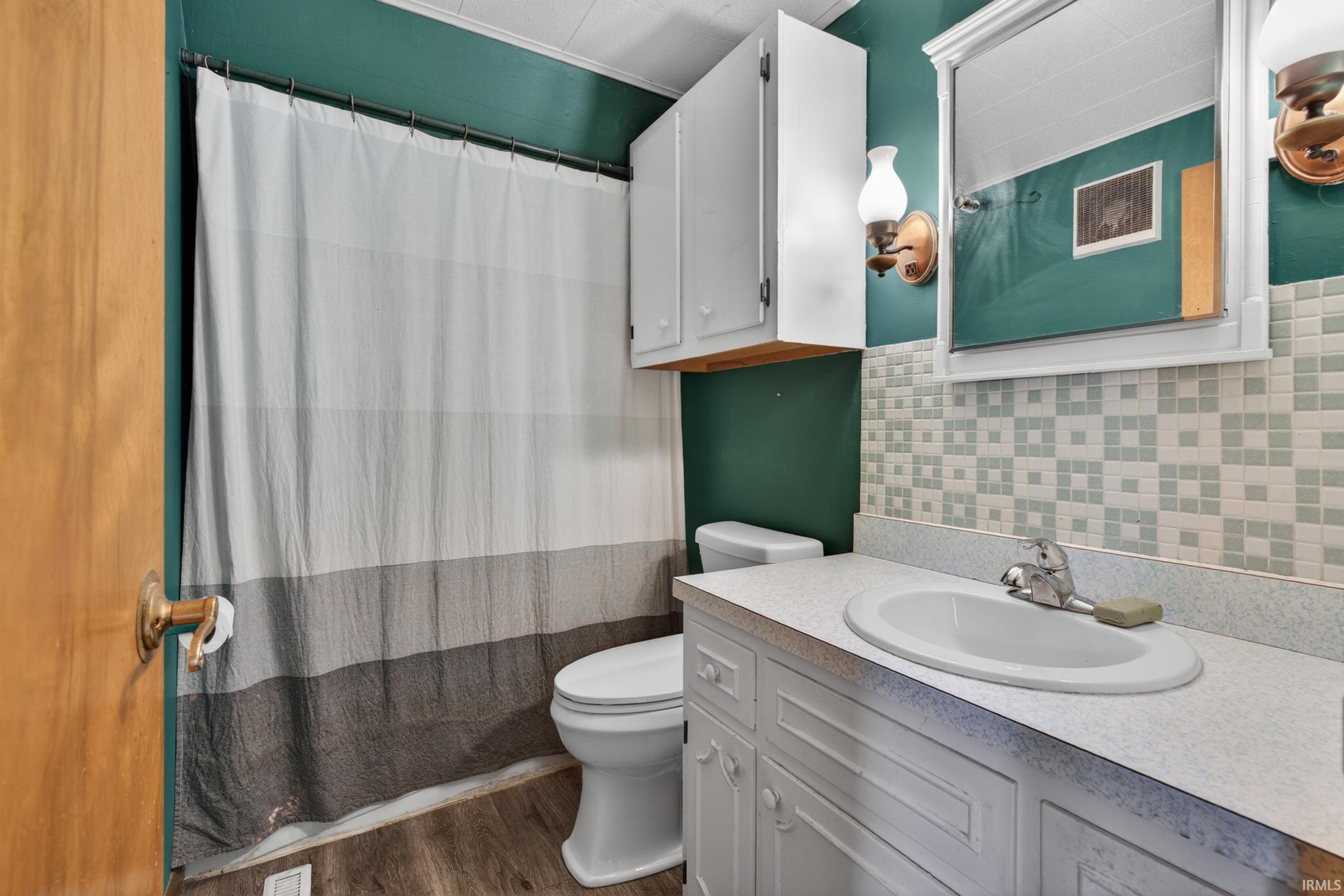 Bathroom featuring wood-finish flooring and a toilet