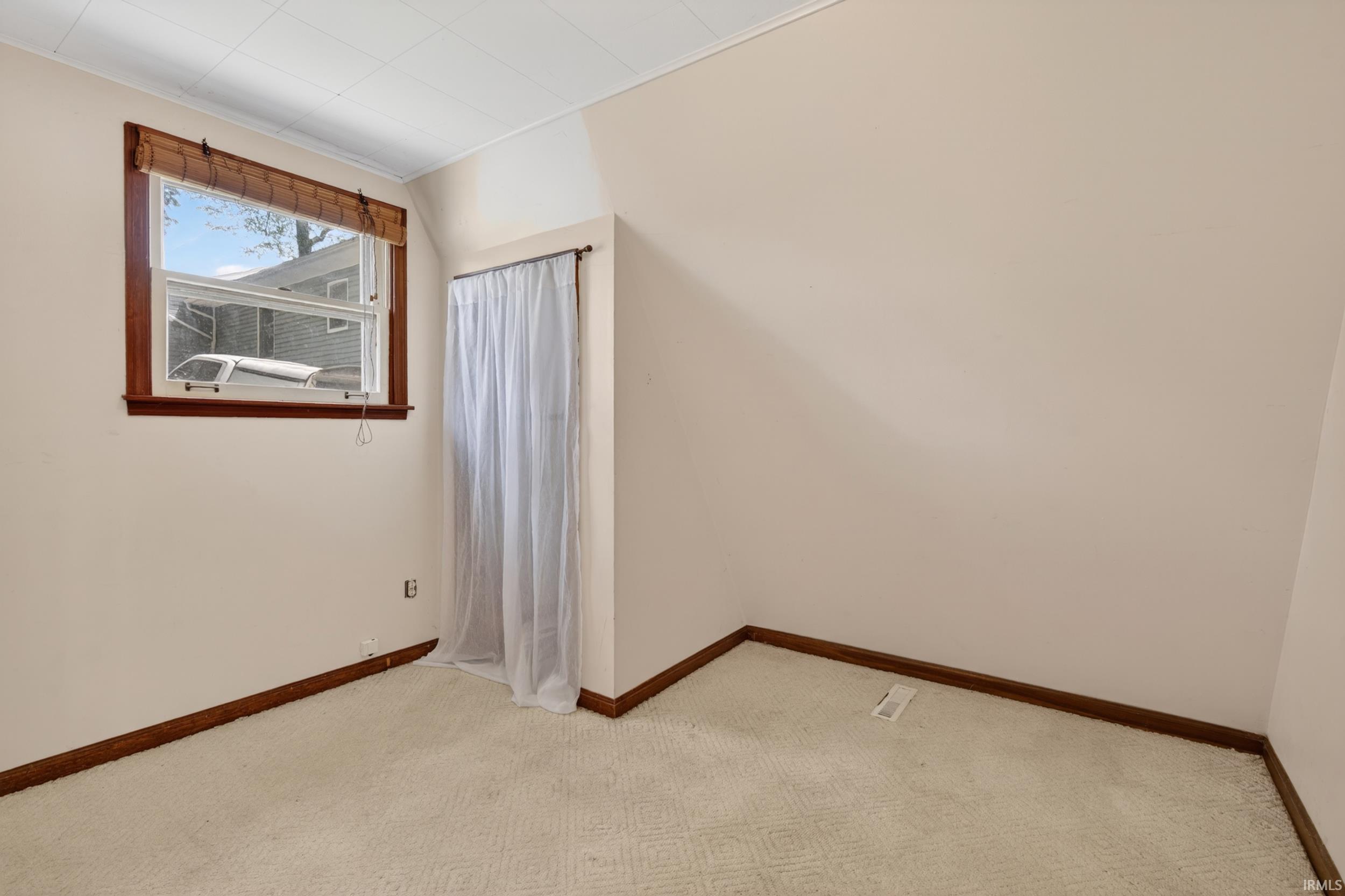Room featuring light-colored walls, patterned carpeting, and wood-finish trim