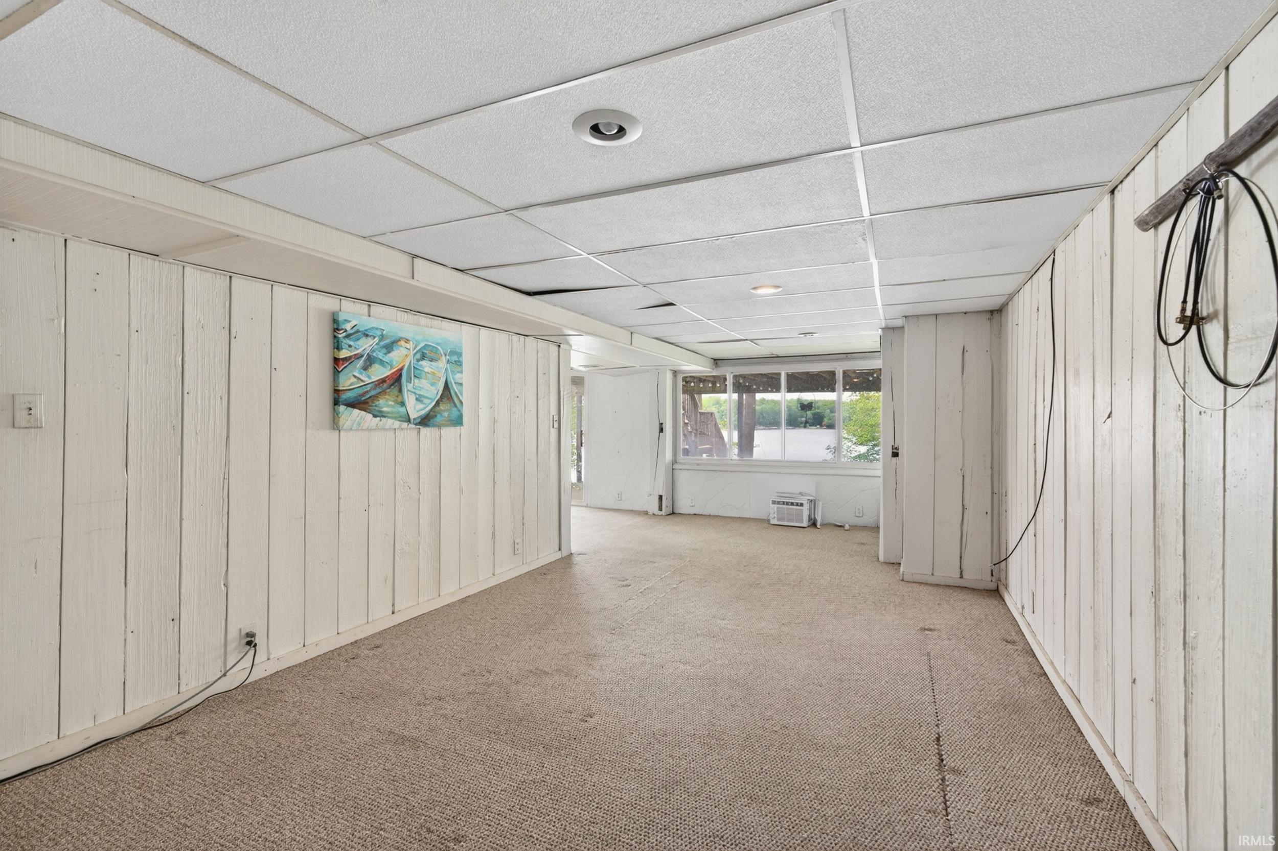 Interior space featuring white paneled walls, a drop ceiling with recessed lighting, and carpet flooring