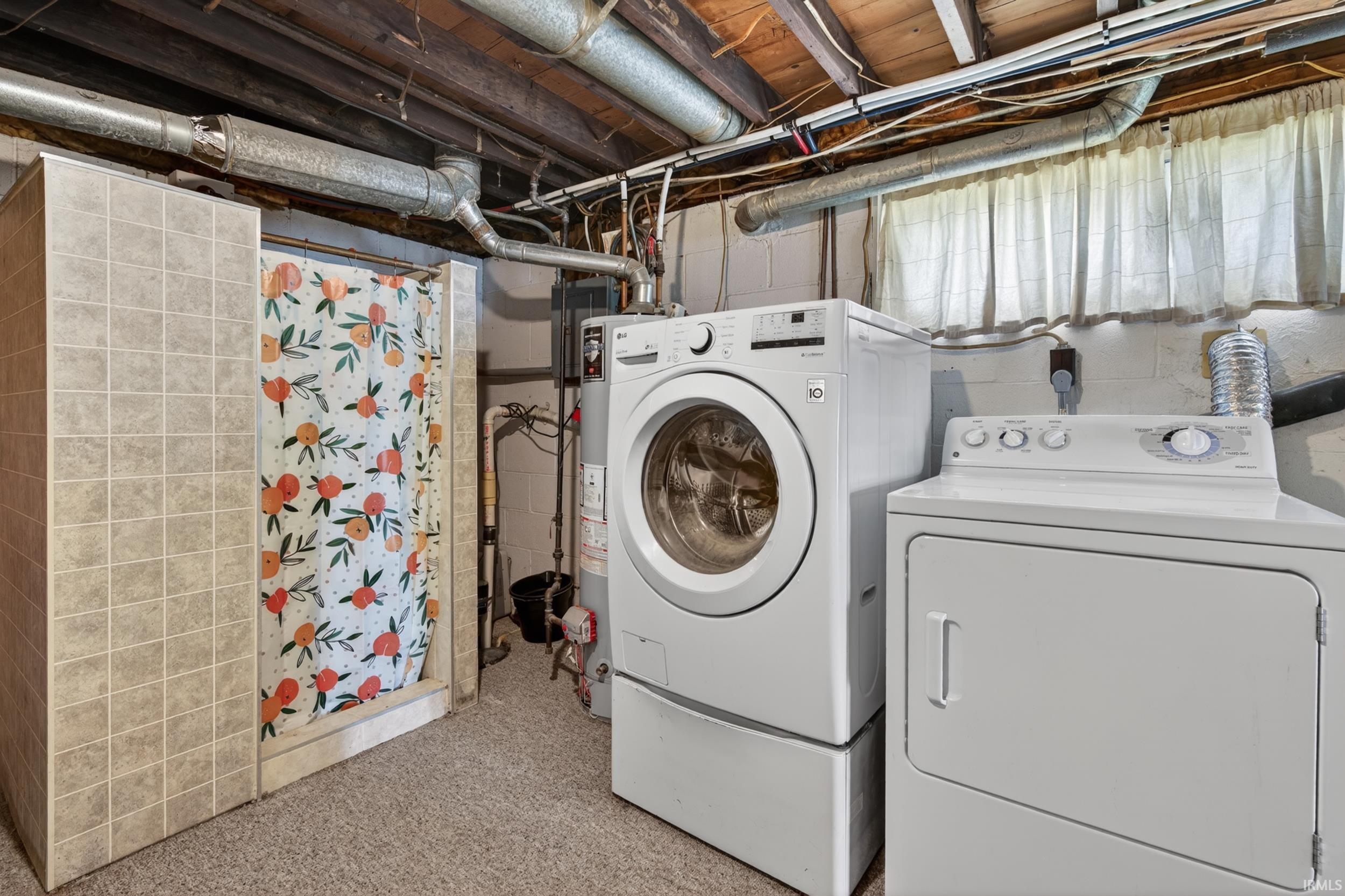 Dedicated laundry area featuring a front-load washer, top-load dryer, and a tiled stand-up shower