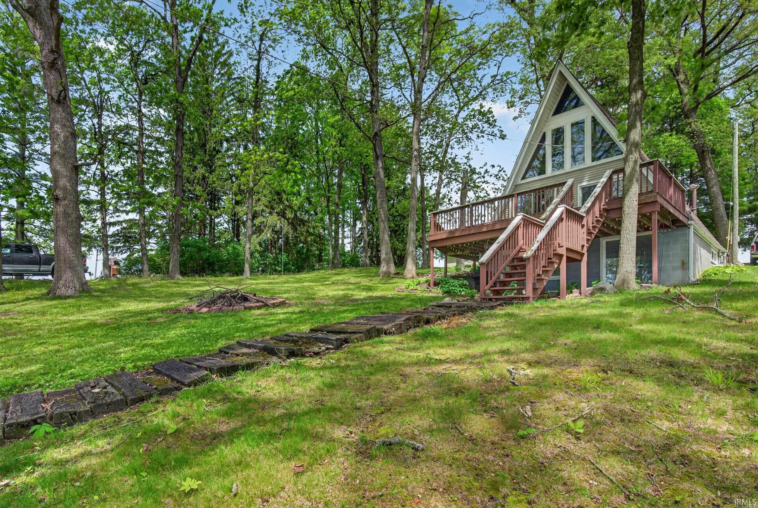 A-frame residence with an elevated wood deck and staircase, set among mature trees