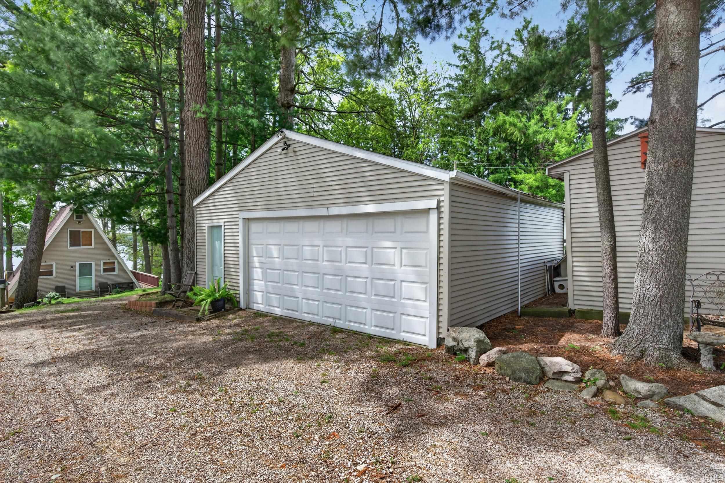 Detached two-car garage with light-toned siding and a panel-style door