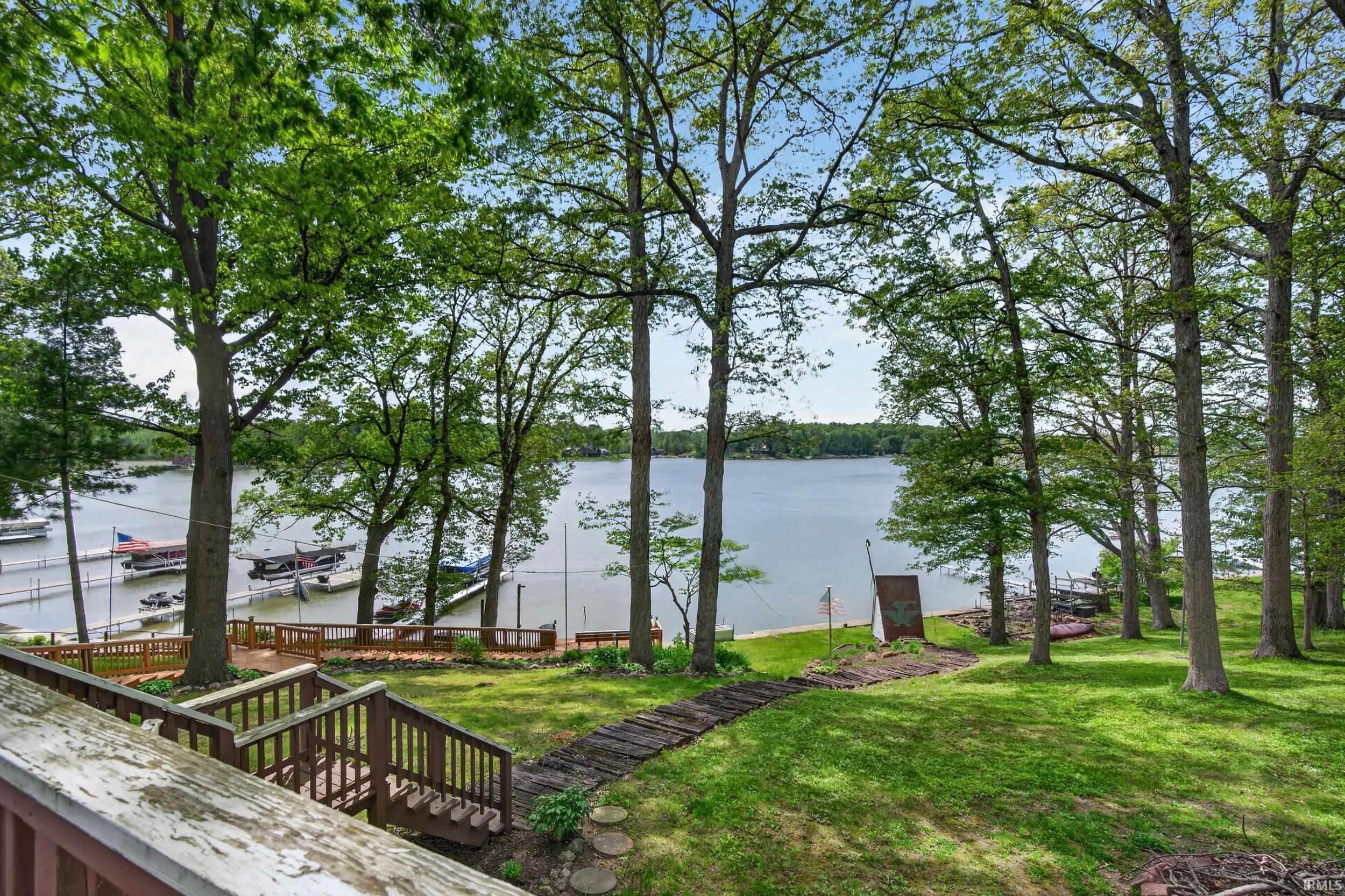 Expansive waterfront property featuring mature trees and a manicured lawn