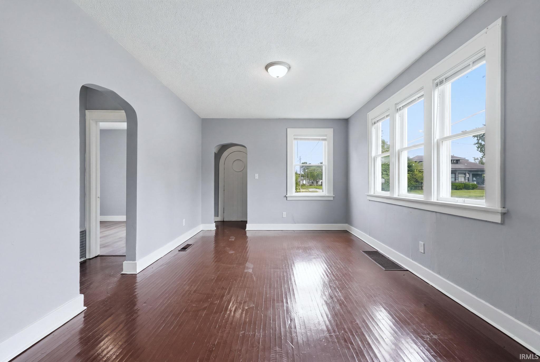 Spacious room featuring wood-finish flooring, light gray walls, and white trim