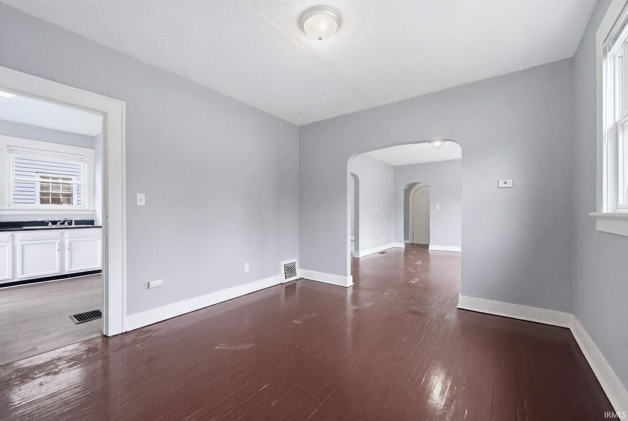 Spacious room featuring wood-finish flooring, light gray wall paint, and white trim