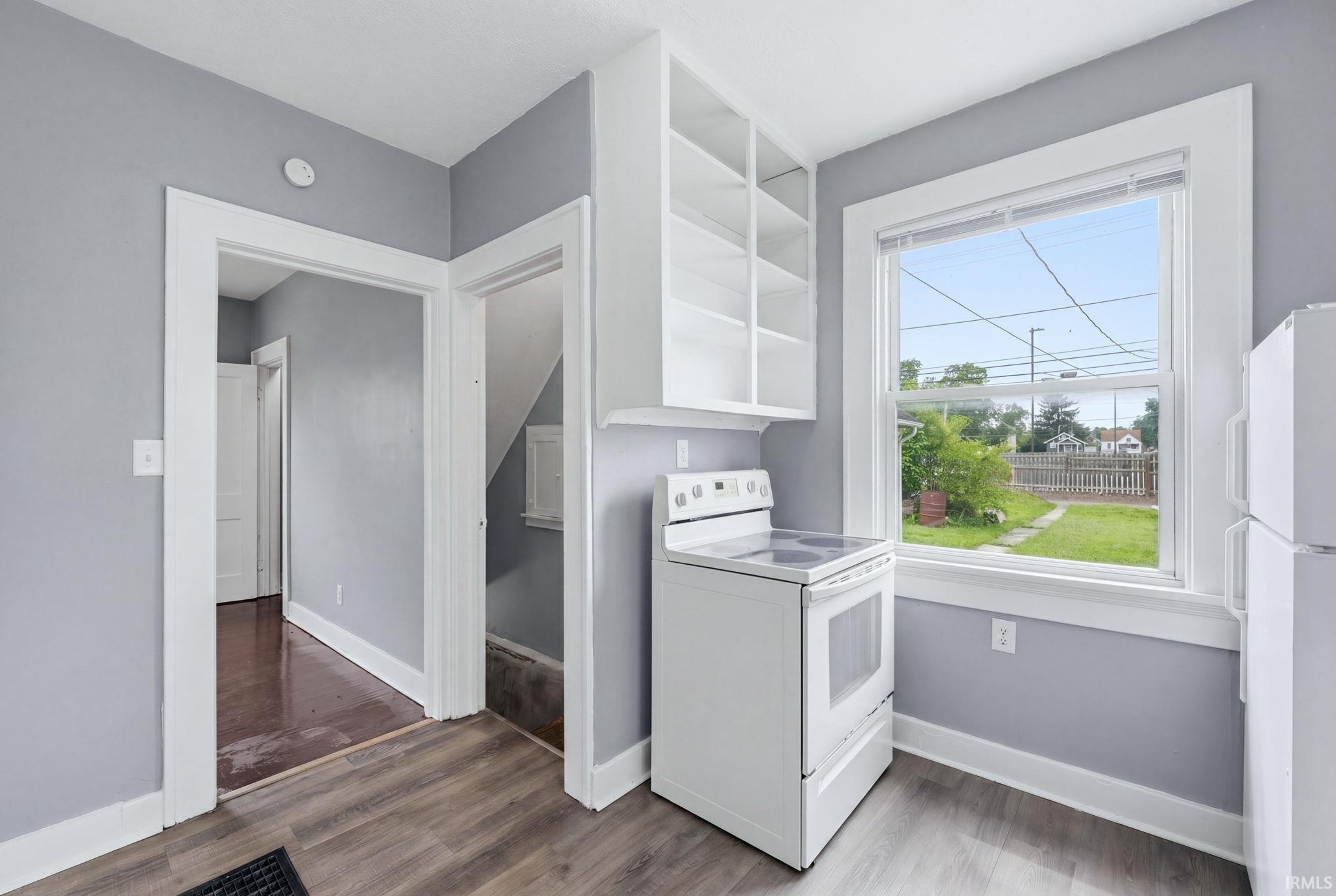 Kitchen area featuring wood-finish flooring, white wall cabinetry, a white electric range, and a white refrigerator