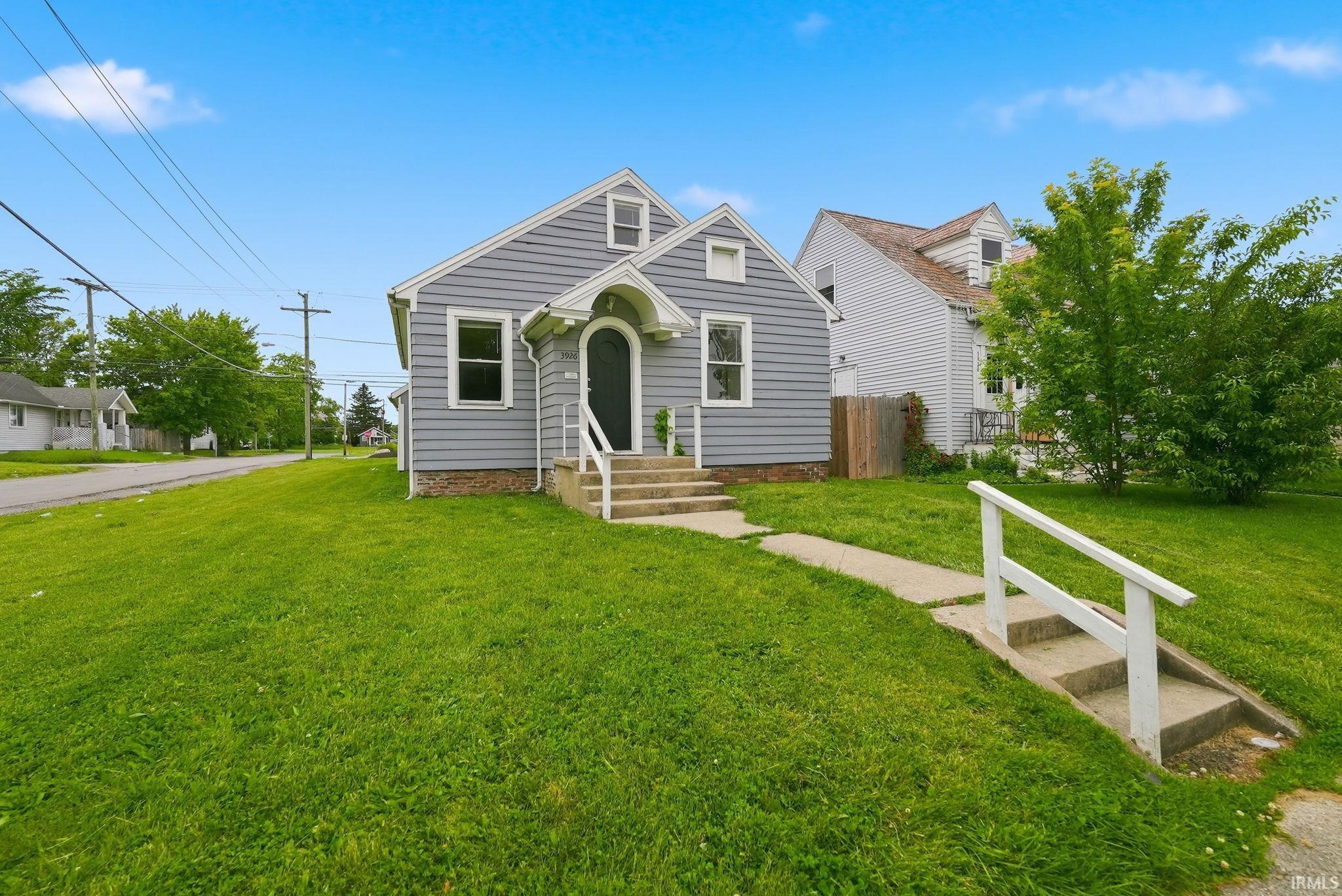 Gray siding exterior with white trim, arched entryway, concrete steps, and a side-facing gable