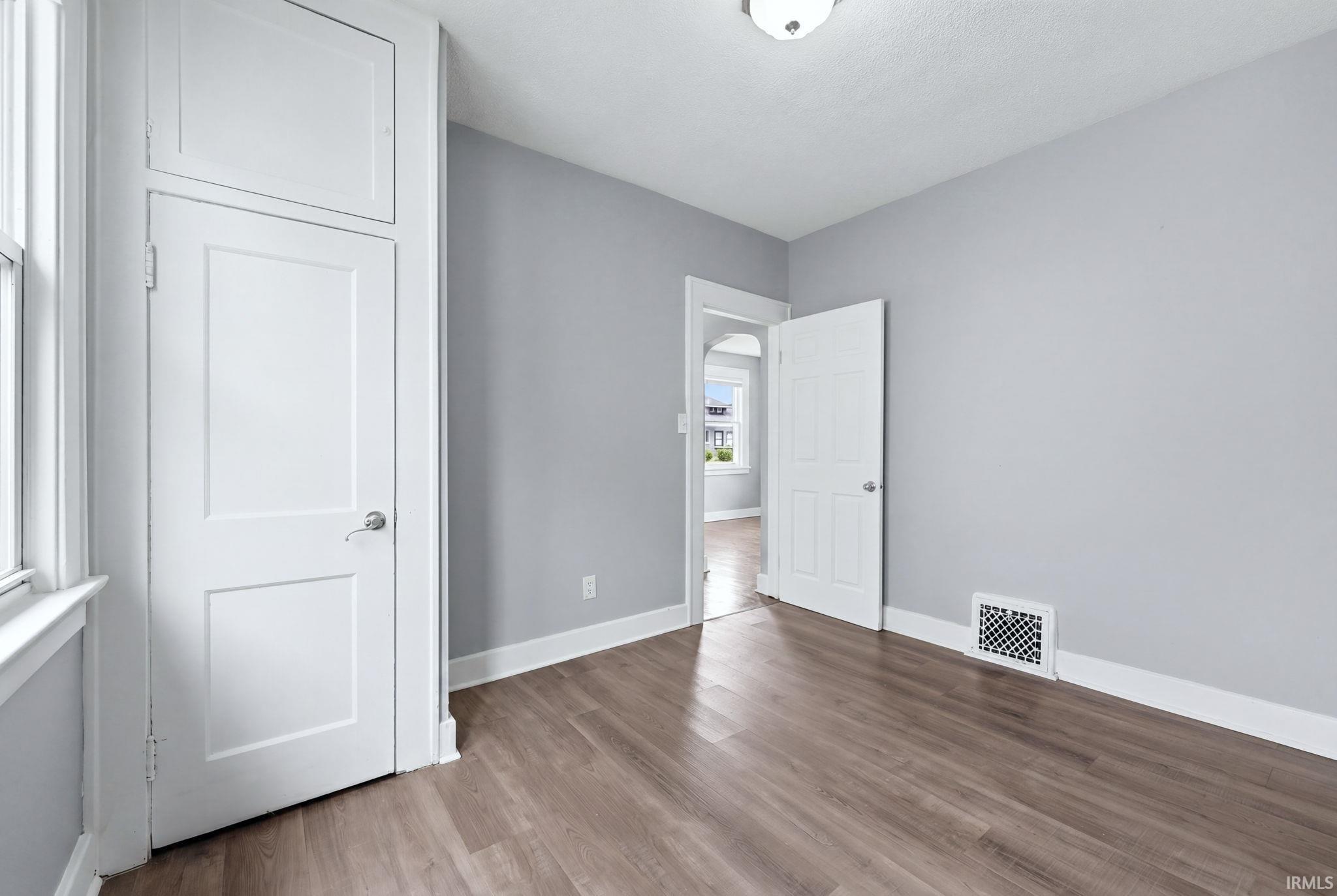 Neutral gray walls featuring wood-finish flooring, white baseboards, and a built-in storage cabinet with paneled doors