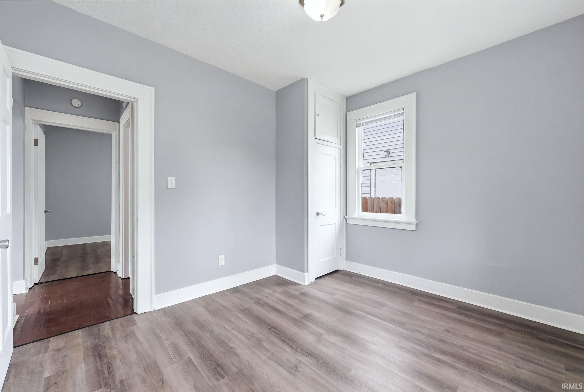 Interior room featuring wood-finish flooring, light gray wall paint, and white trim