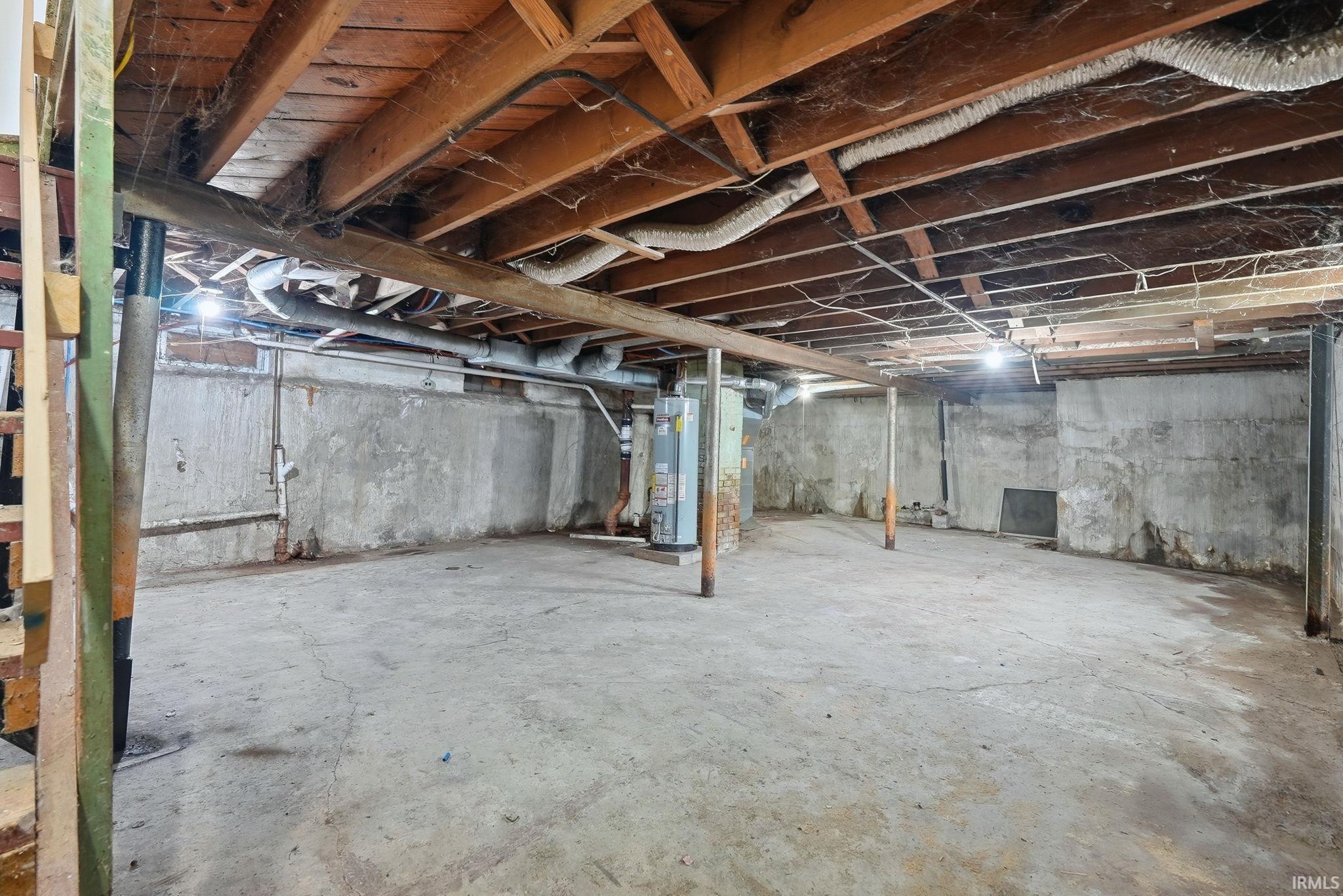 Unfinished basement featuring exposed wood joists, concrete flooring, and solid concrete walls