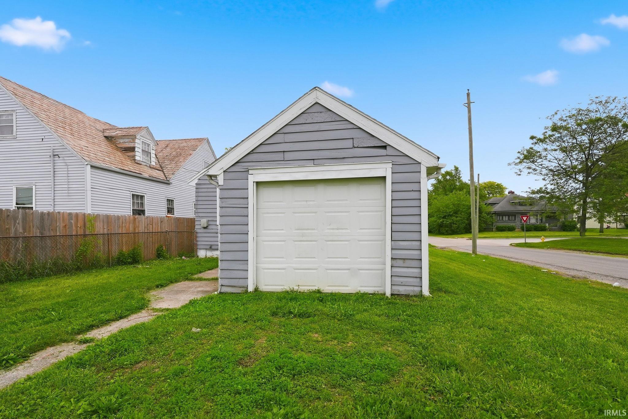 Detached garage with horizontal gray siding and a white overhead door