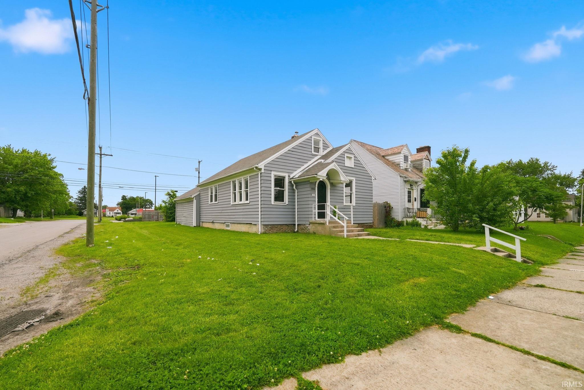 Exterior features include light gray siding, white trim, a covered front entry with white railings, and a side-attached garage with a matching exterior
