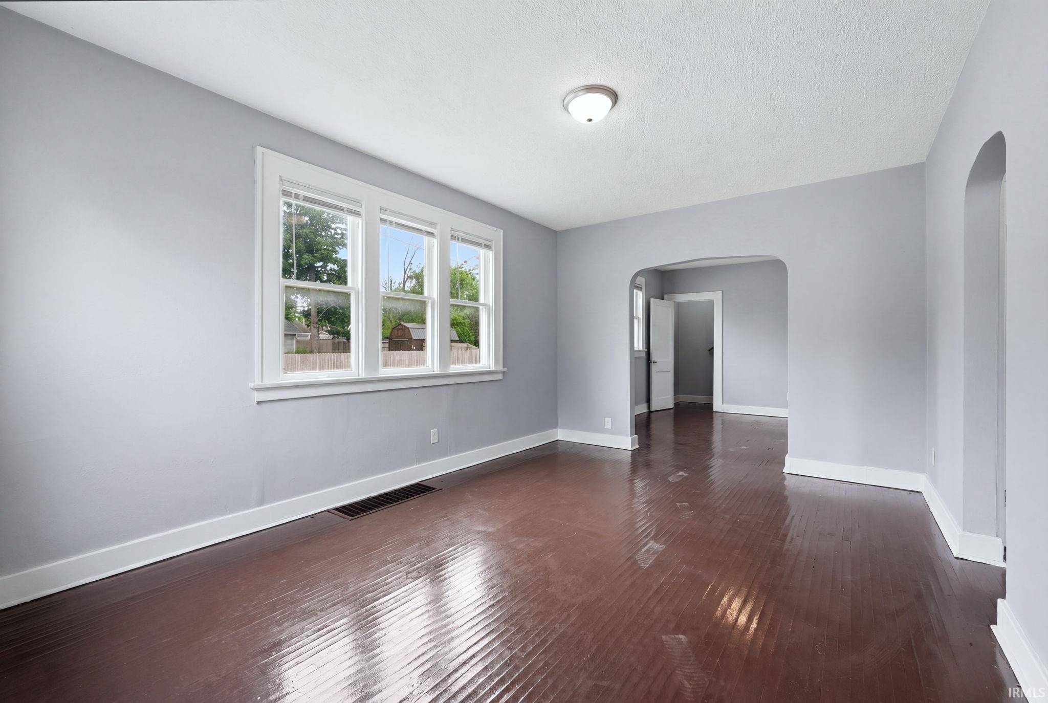 Hardwood flooring extends throughout this room, featuring light gray walls, white trim, and a three-pane window