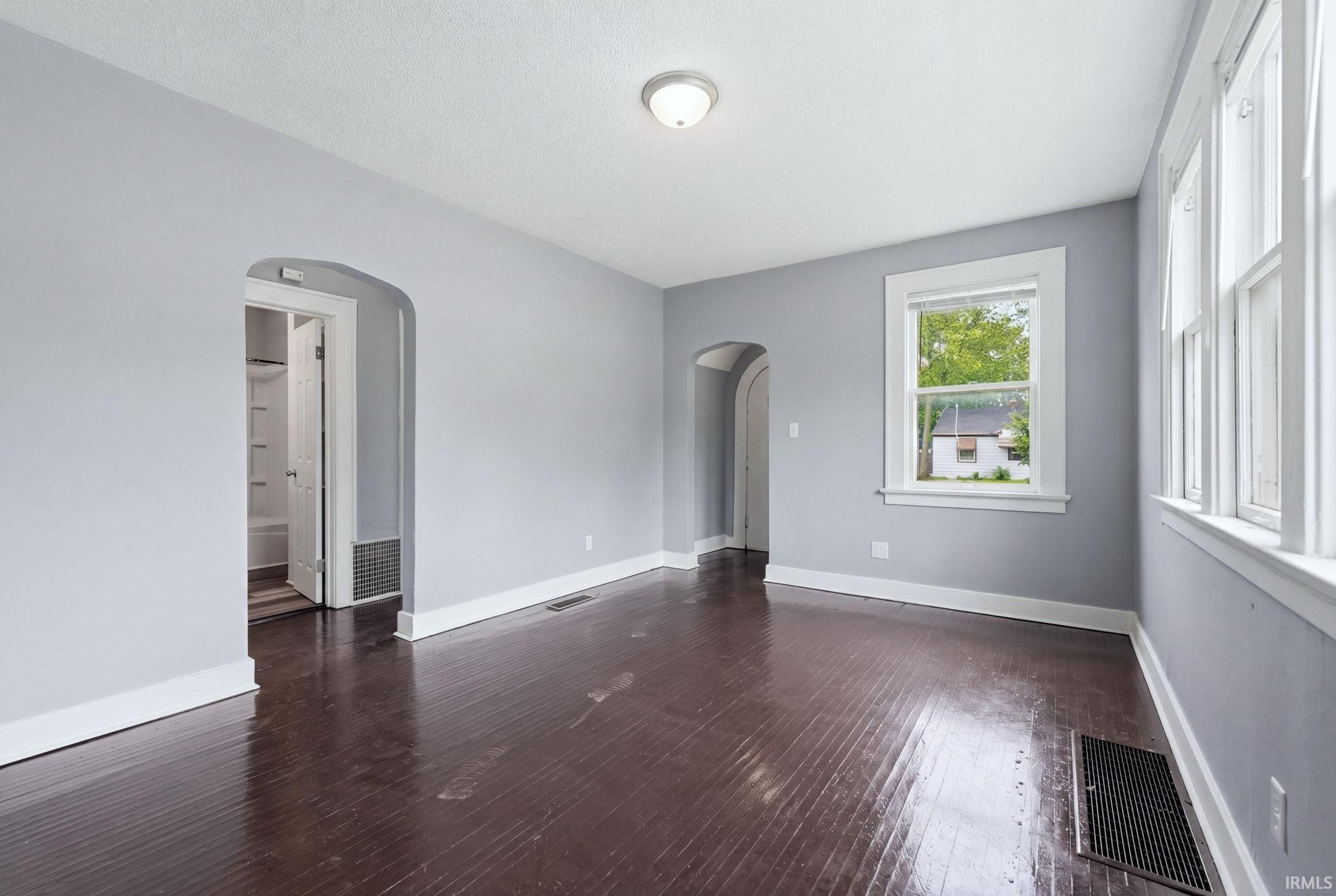 Spacious room featuring dark wood-finish flooring, light gray walls, and white trim throughout