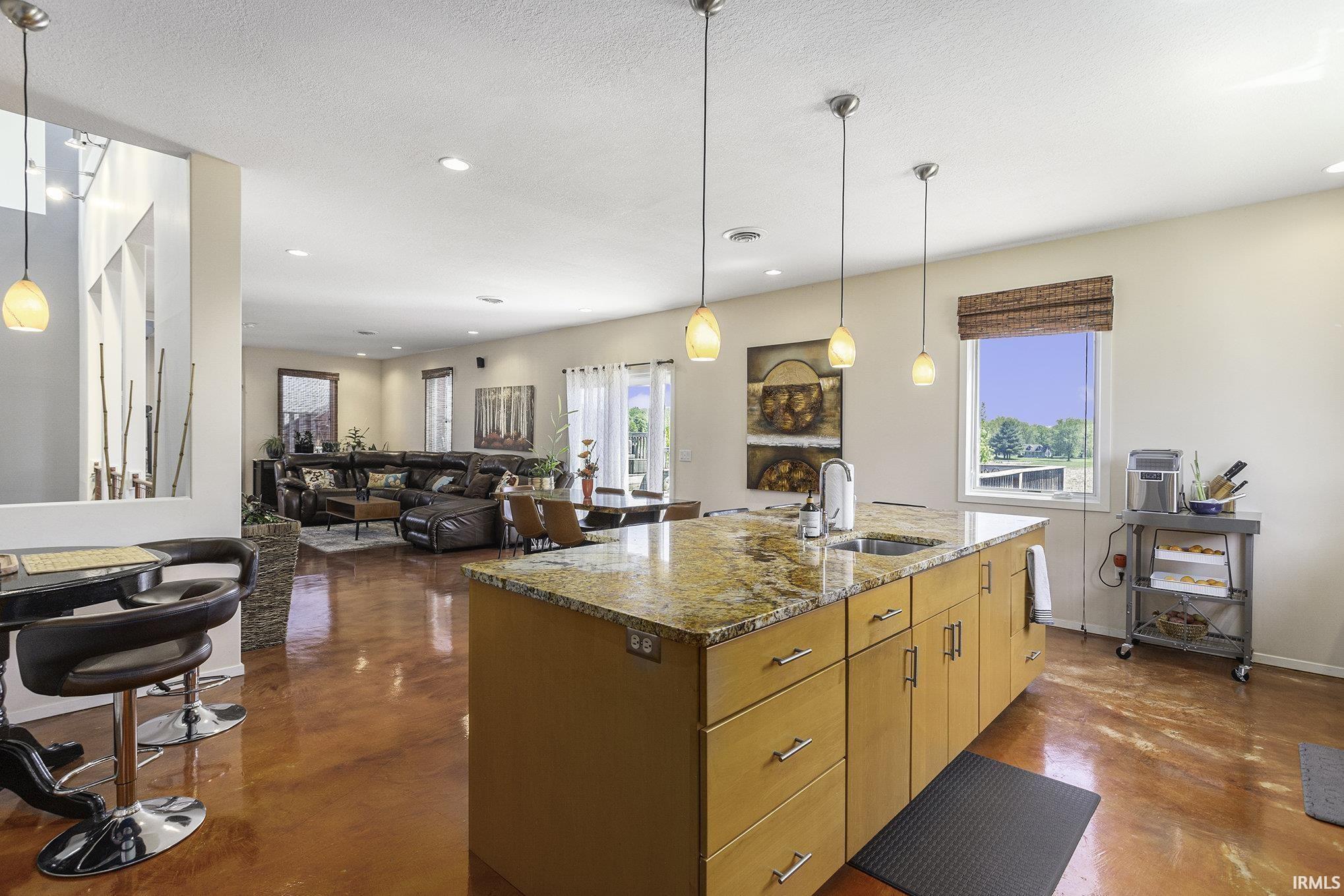 Spacious kitchen island featuring a granite countertop, integrated sink, and ample cabinetry