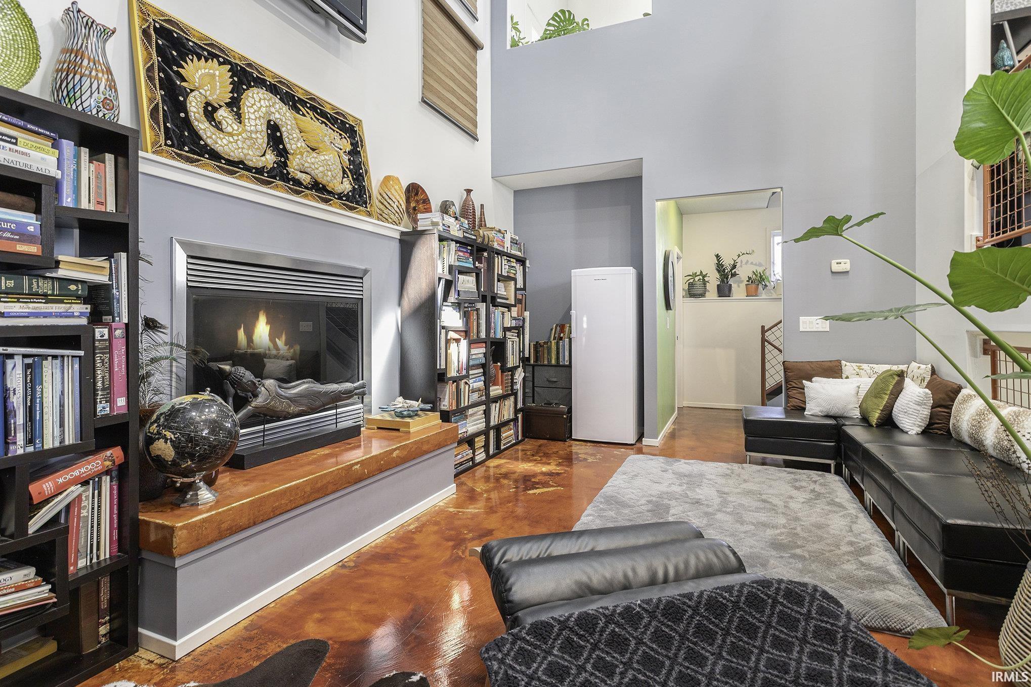 Spacious living area featuring high ceilings, a built-in fireplace with a hearth, and durable polished concrete flooring