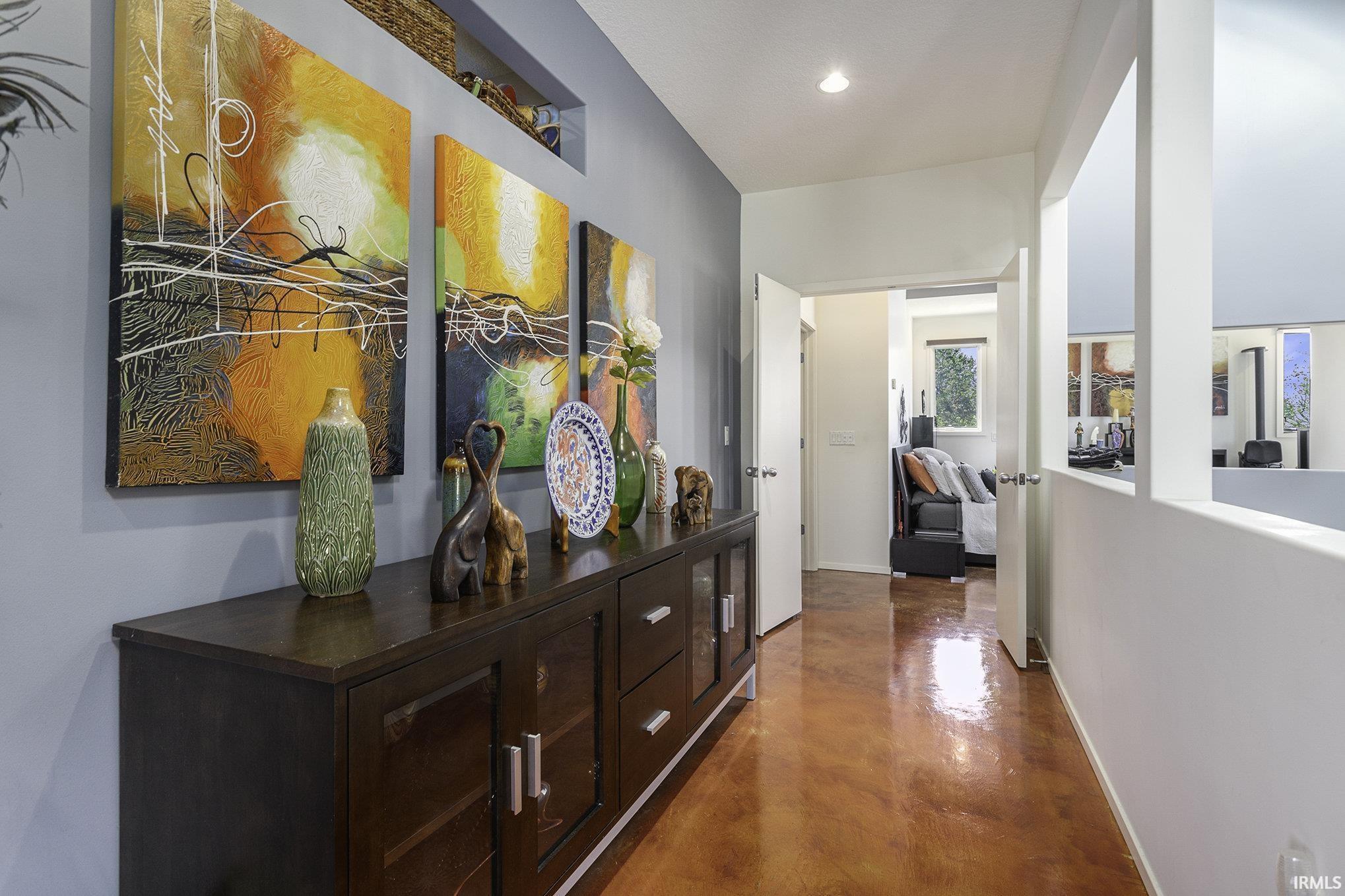 Hallway featuring rich amber-toned flooring, a built-in wall niche, and a contrasting white half-wall railing