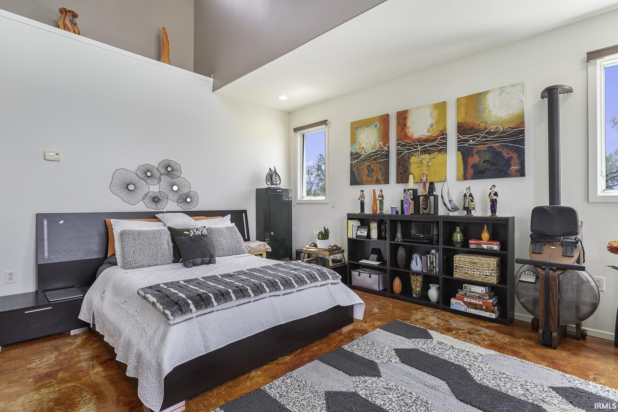 Loft-style ceiling with an upper shelf, multiple windows, and stained concrete flooring