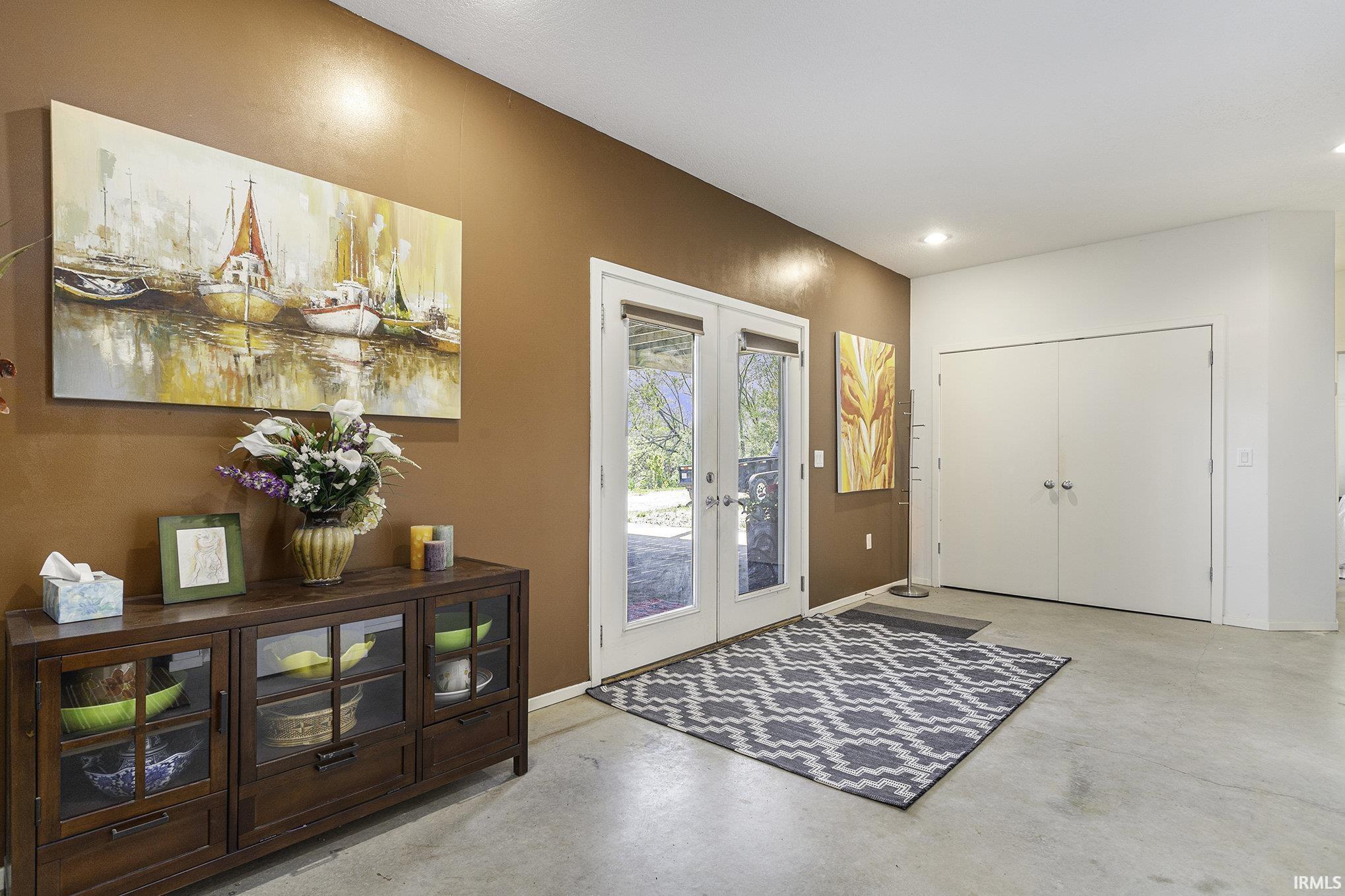 Entryway featuring concrete-finish flooring, recessed lighting, and a brown accent wall