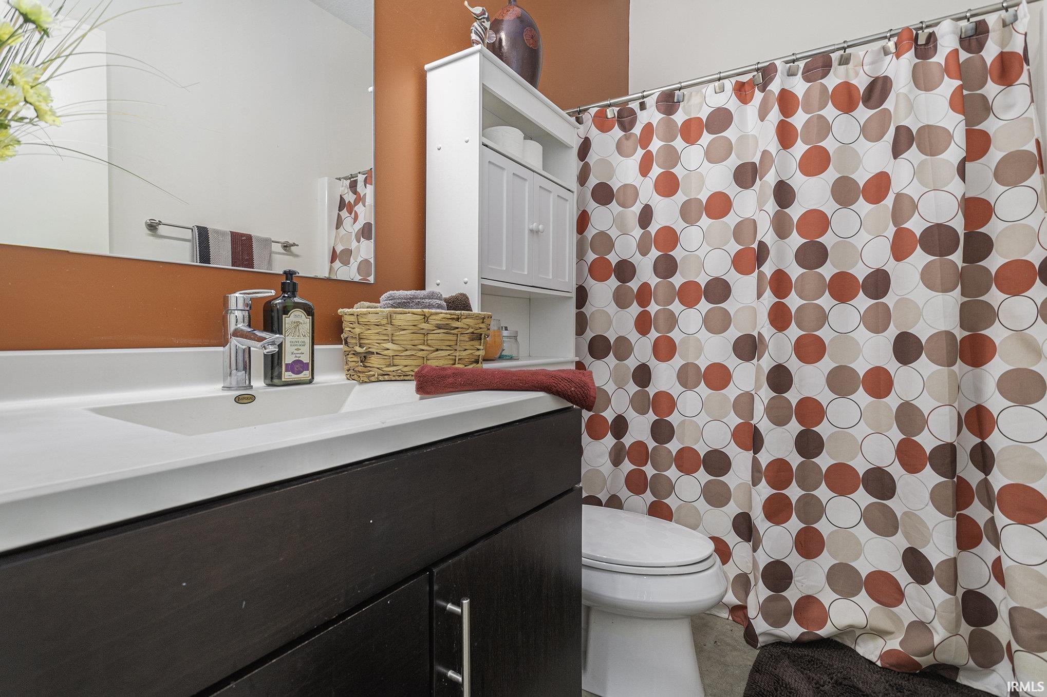 Bathroom featuring a dark wood-finish vanity with an integrated sink, polished chrome faucet, and a large wall-mounted mirror